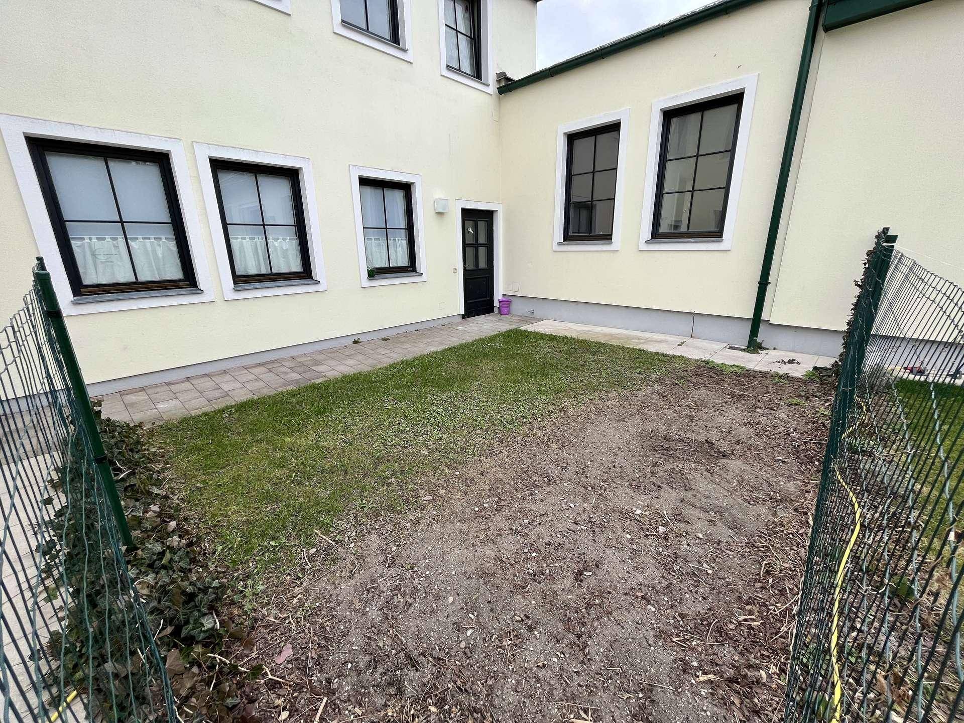 Kleiner Gartenbereich hinter dem Haus mit Rasenfläche und Zaun, bereit zur Gestaltung.