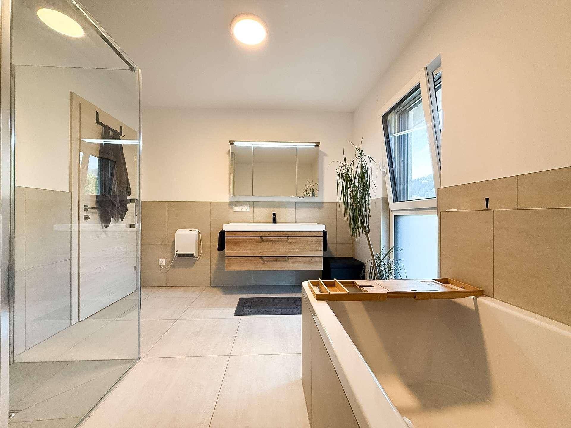 Helles Badezimmer mit Badewanne, Dusche, Einzelwaschbecken und Spiegelschrank.