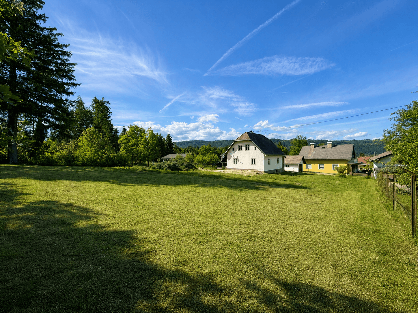 Weitläufige Grünfläche mit Blick auf das Einfamilienhaus und die umliegende Natur.