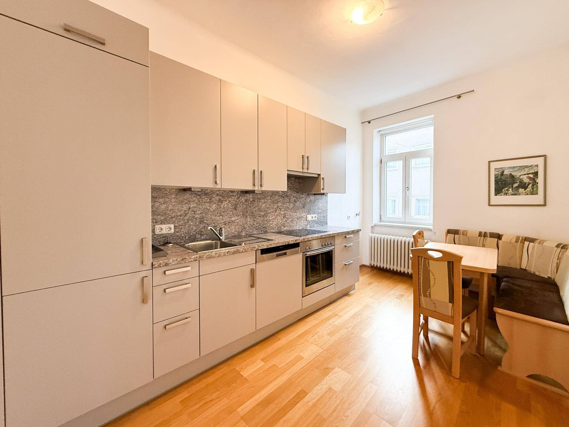 Moderne Einbauküche mit Essbereich, hellen Schränken und Holzboden.