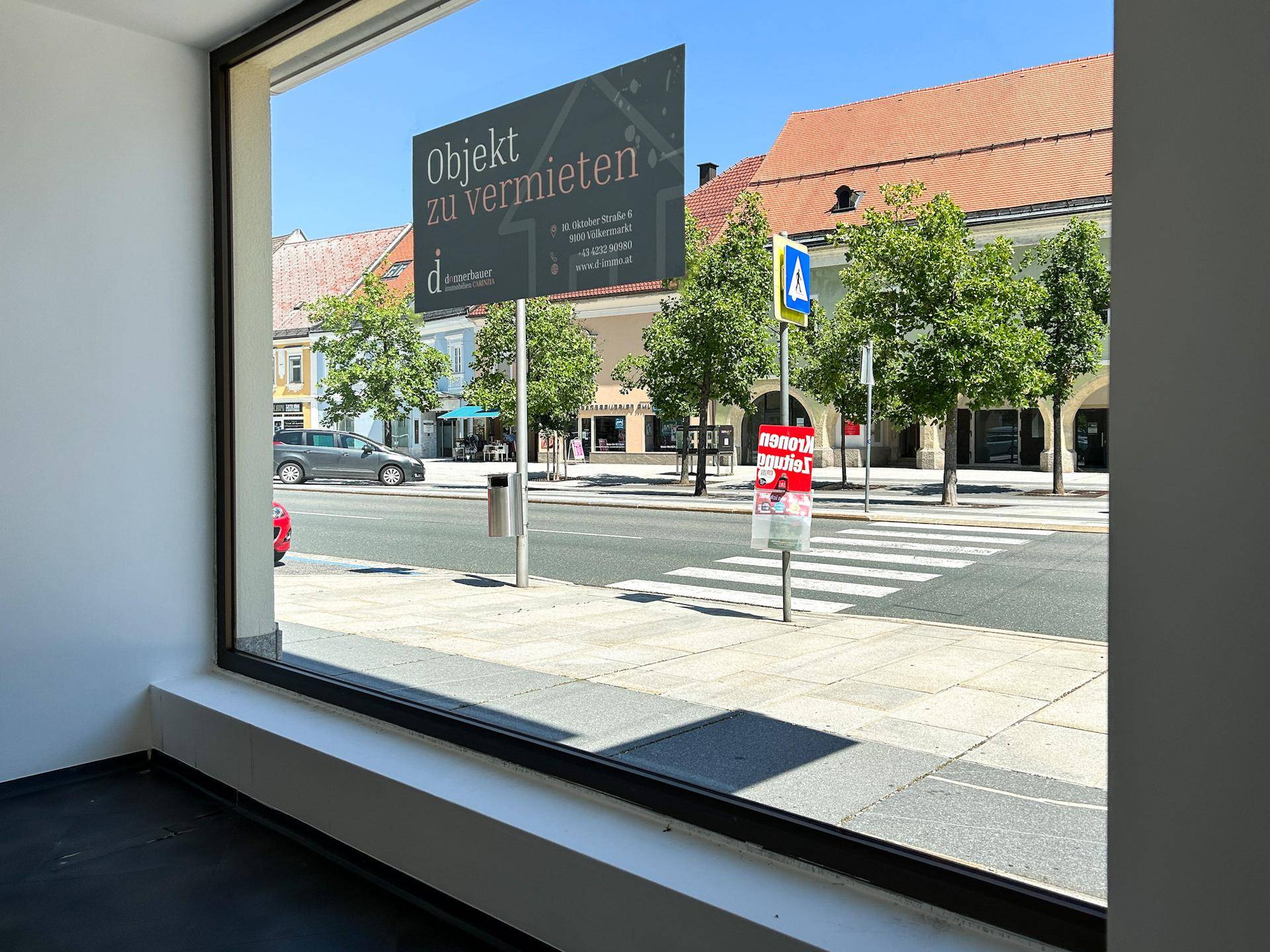 Blick aus einem großen Schaufenster auf die belebte Straße mit einem 'Objekt zu vermieten'-Schild.