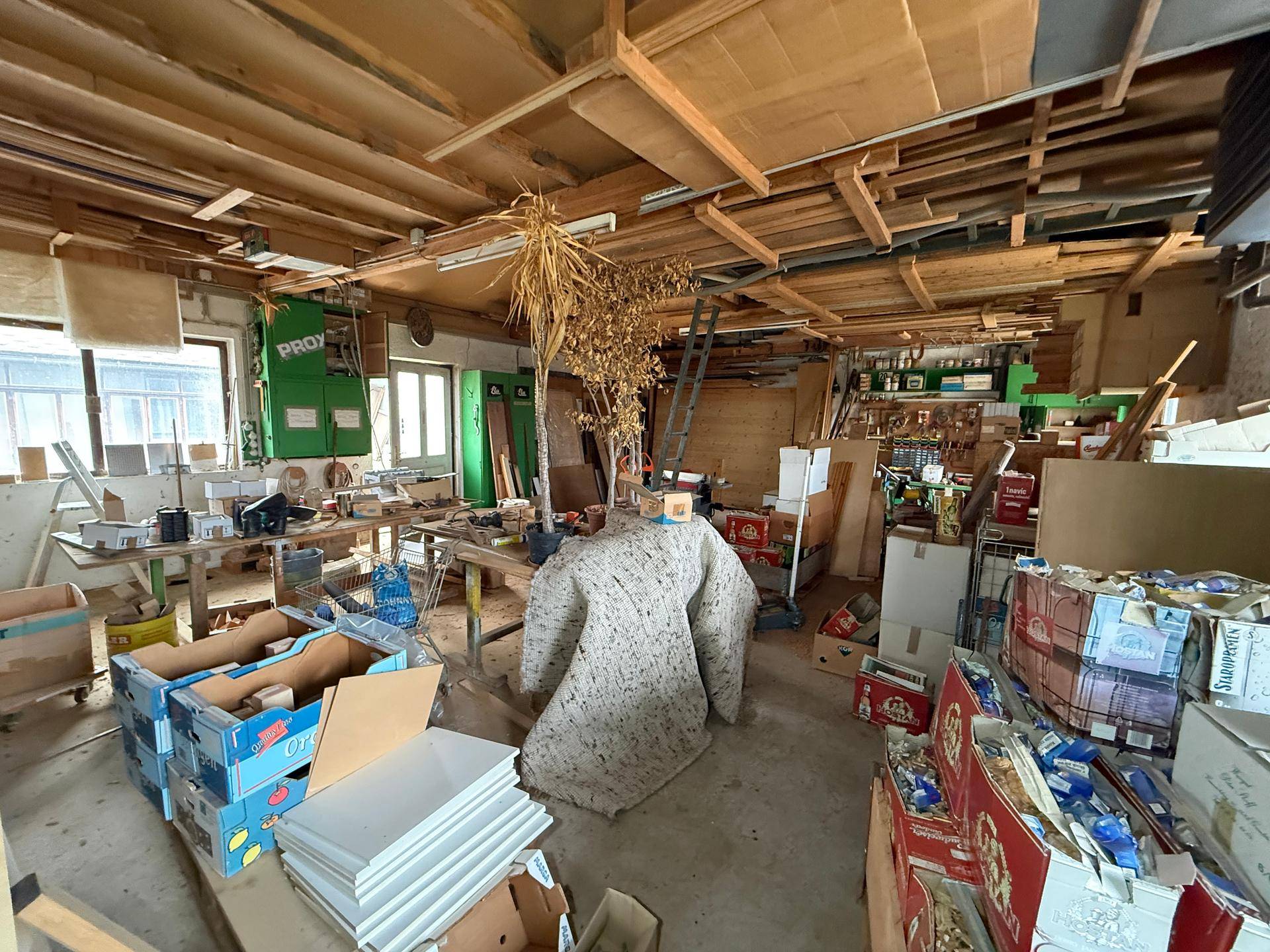 Großer Werkstattraum mit Holzbalken, vielen Materialien und Werkzeugen.
