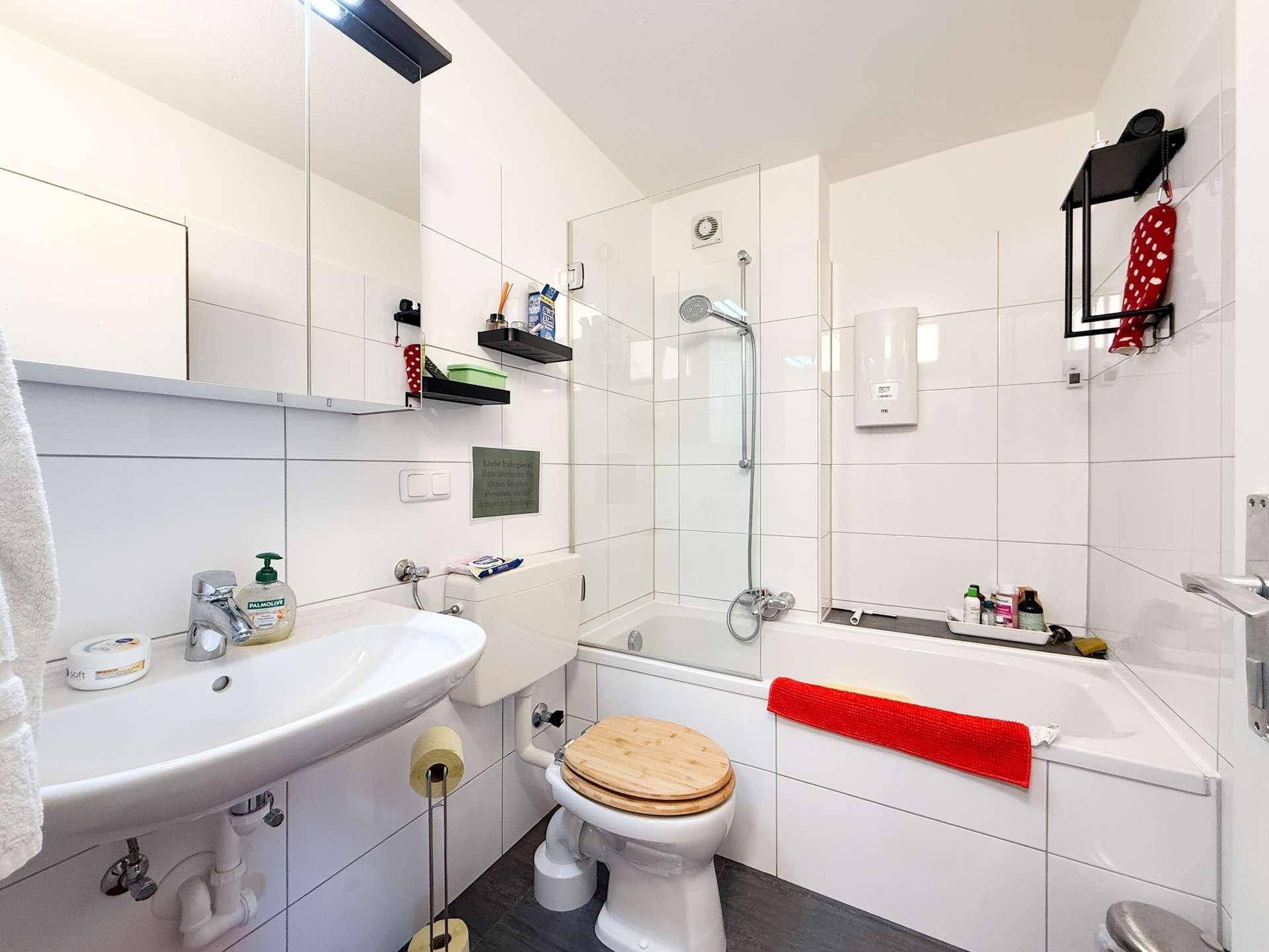 Modernes Badezimmer mit Badewanne, integrierter Dusche, WC und Waschbecken.