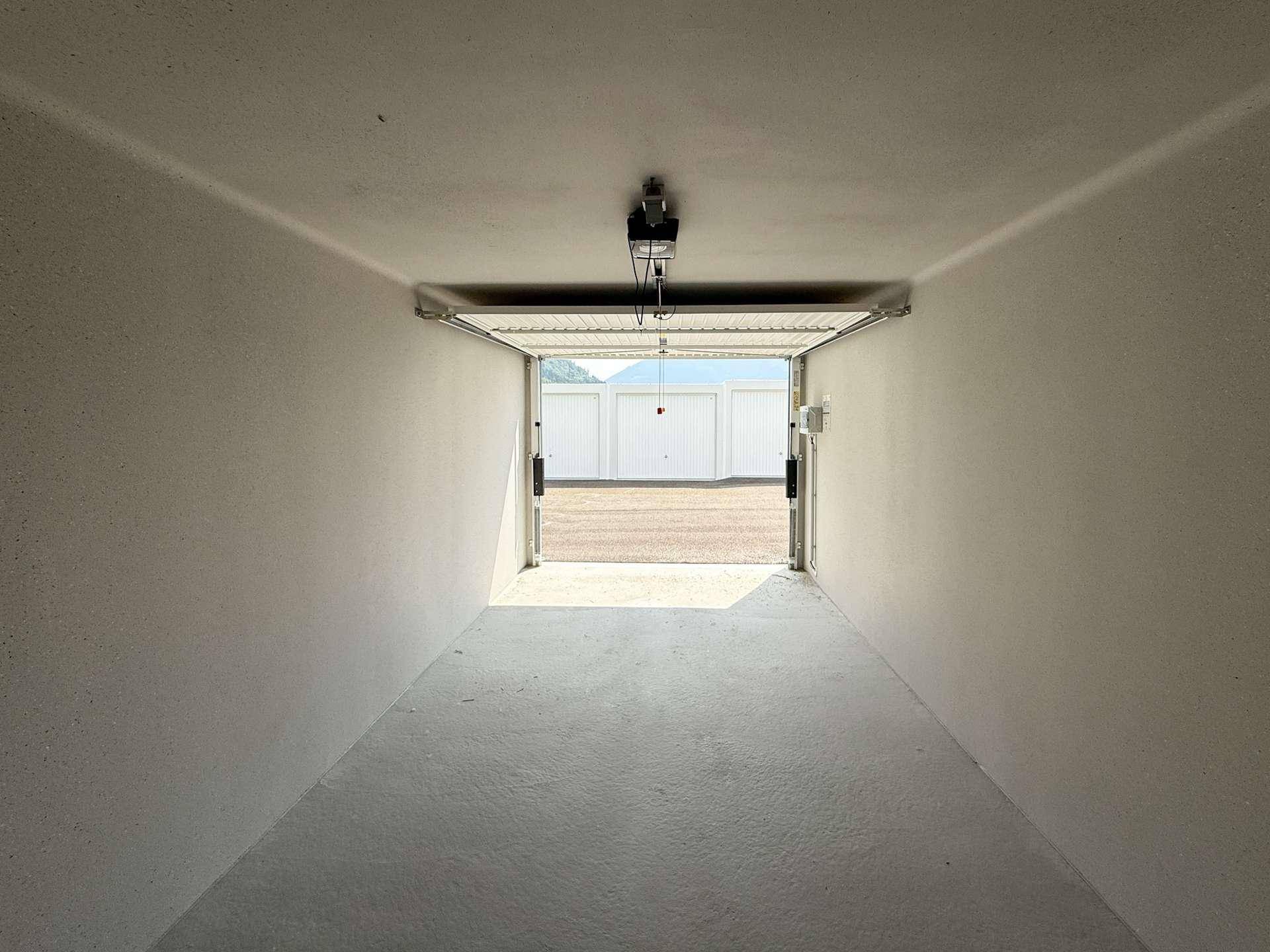 Blick aus einer leeren Garagenbox auf weitere Garagen und den Außenbereich.