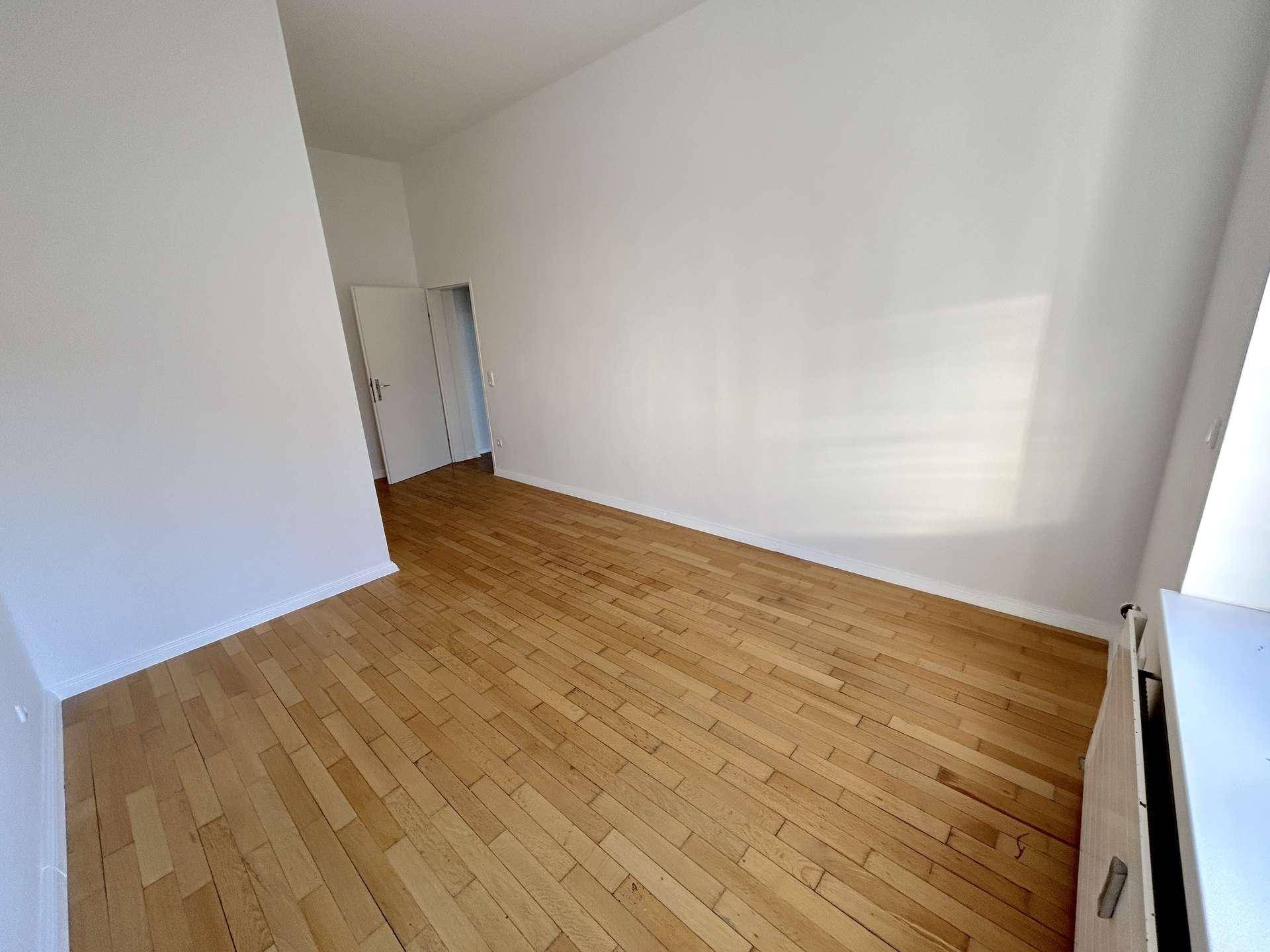 Leeres Zimmer mit klassischem Holzboden und weißer Wandfarbe, bietet vielseitige Nutzungsmöglichkeiten.
