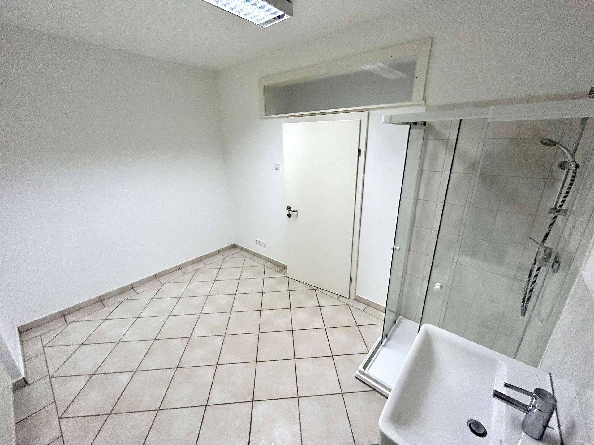 Kompaktes Badezimmer mit Duschkabine und Waschbecken, ideal für kleine Wohnungen.