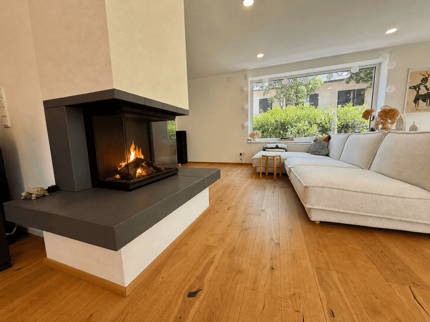 Gemütliches Wohnzimmer mit modernem Kamin, bequemer Couch und Holzboden.