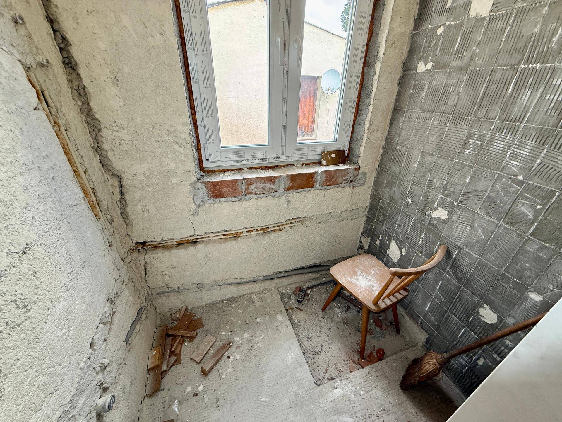 Raum im Rohbauzustand mit Fenster, bereit für die Renovierung.