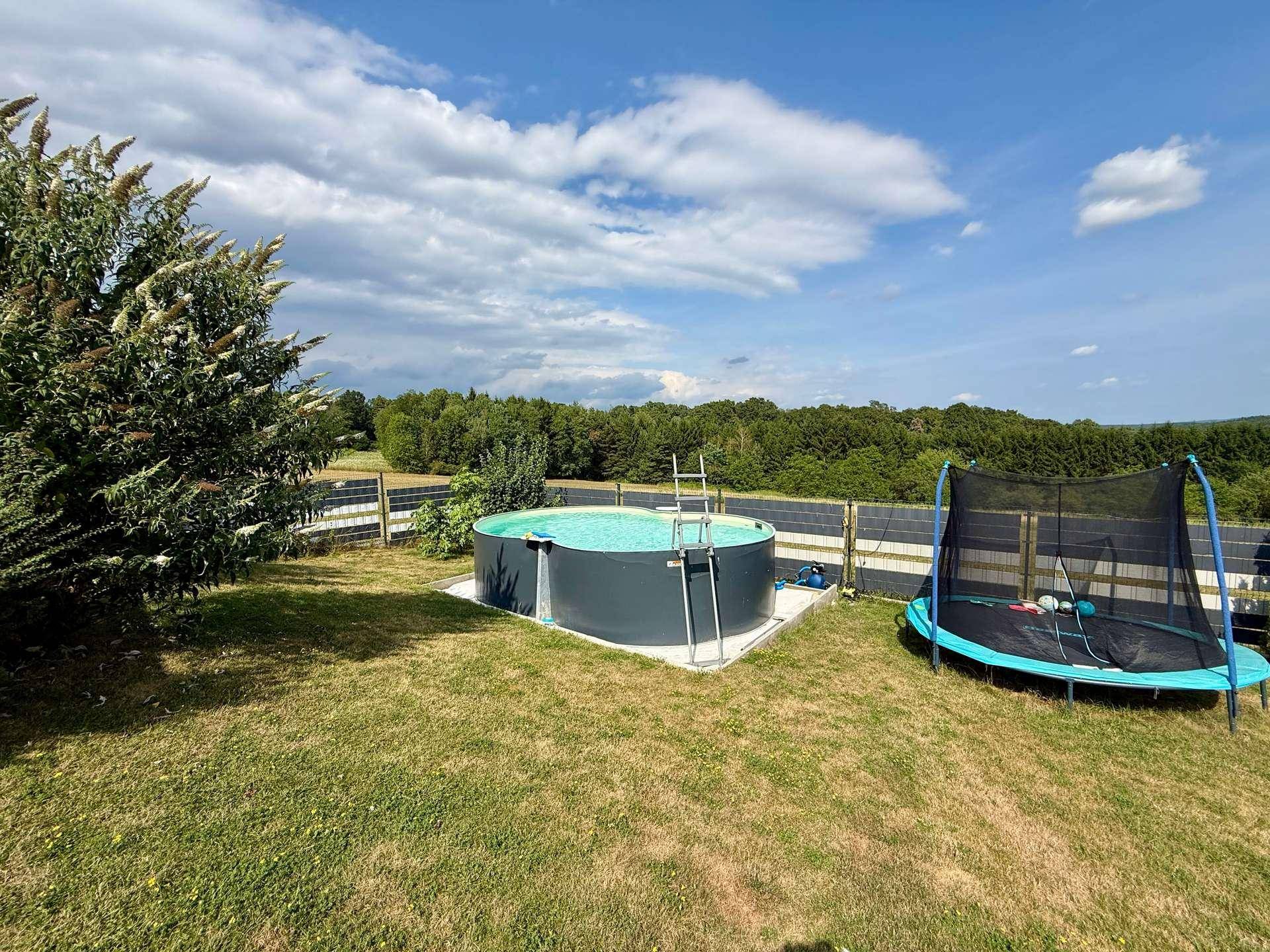 Großer Garten mit Aufstellpool und Trampolin, ideal für Freizeitaktivitäten im Freien.