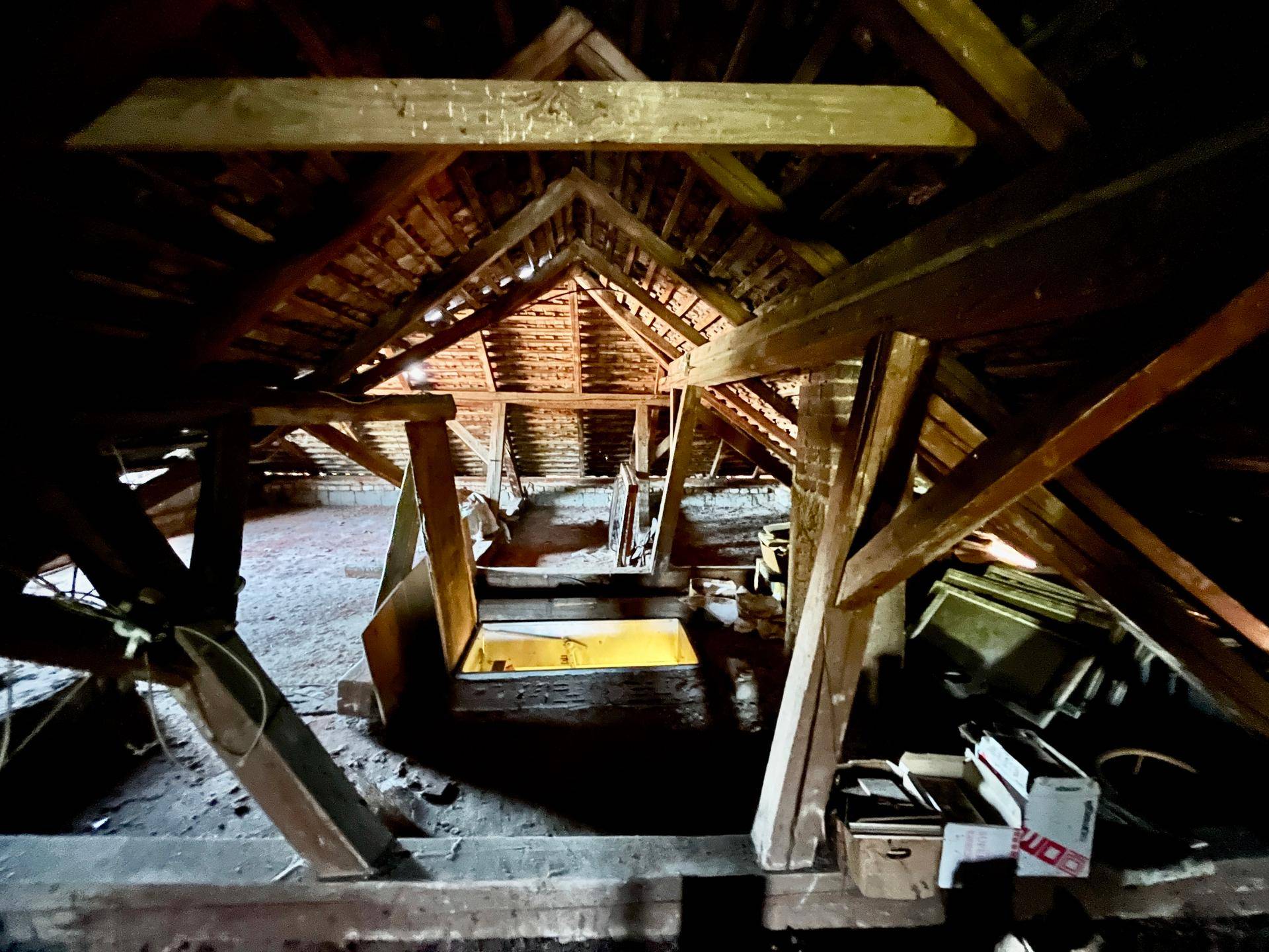 Unausgebauter Dachboden mit sichtbaren Holzbalken und viel Stauraum.