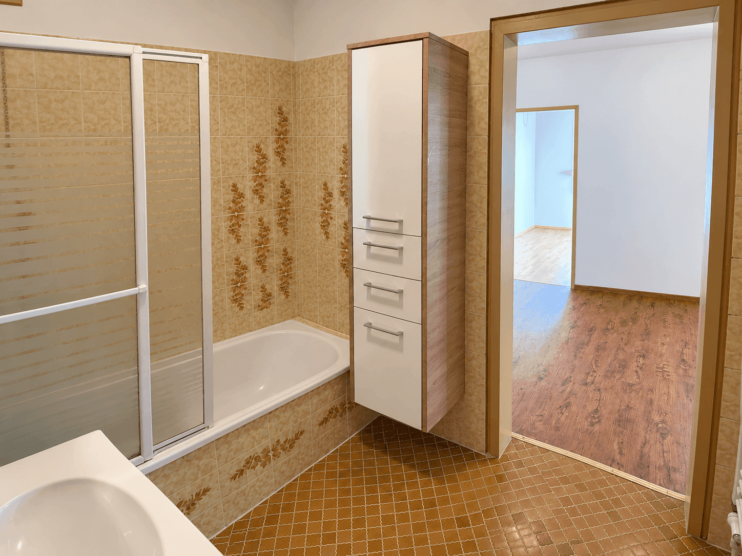 Badezimmer mit Badewanne, Duschabtrennung und Fliesen in warmen Brauntönen, funktional ausgestattet.