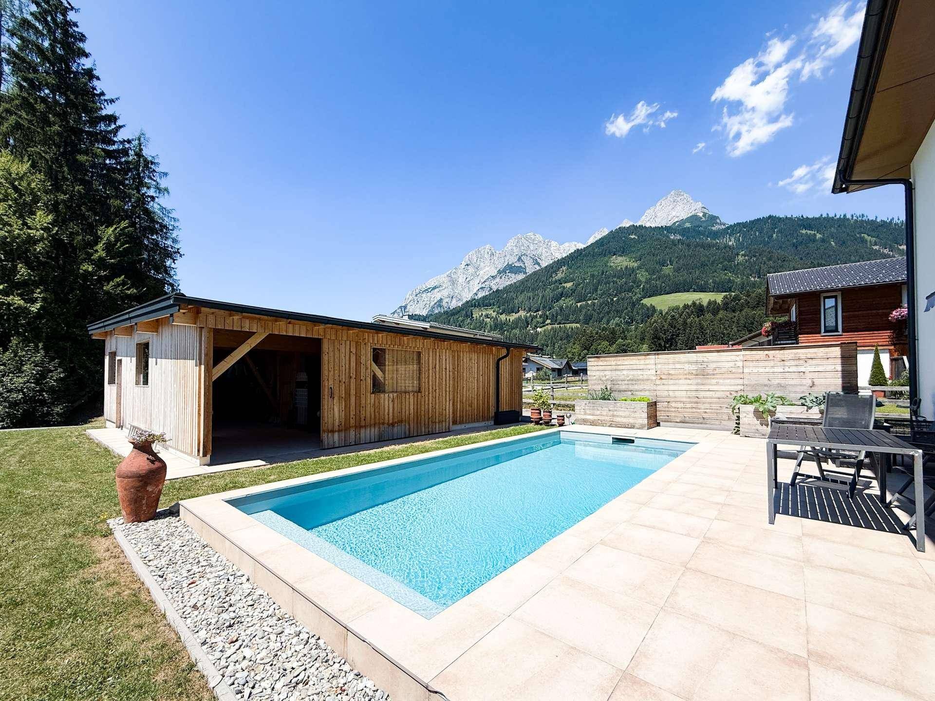 Entspannender Poolbereich mit Holzgebäude und malerischem Blick auf die umliegenden Berge.