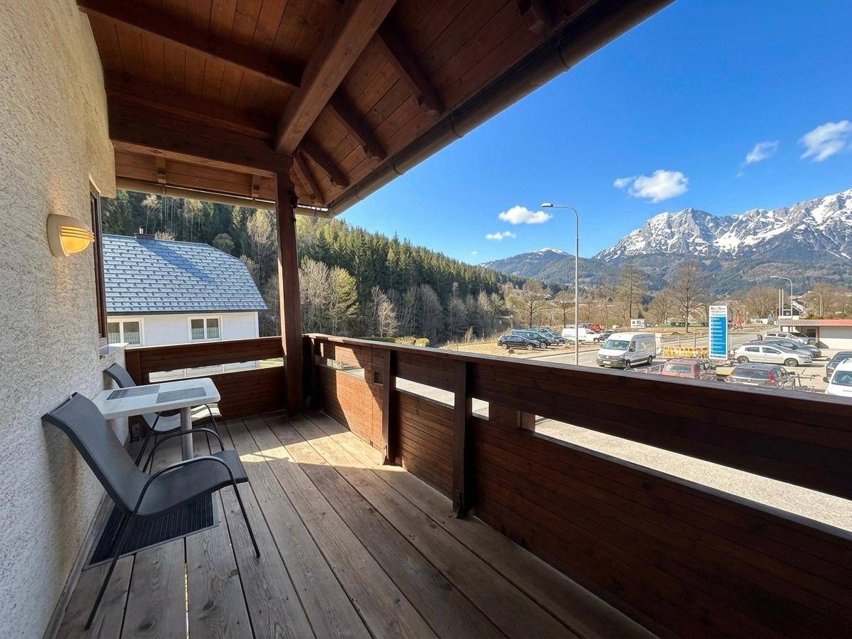 Sonniger Balkon mit Sitzgelegenheiten und weitem Blick auf die Berge und Umgebung.