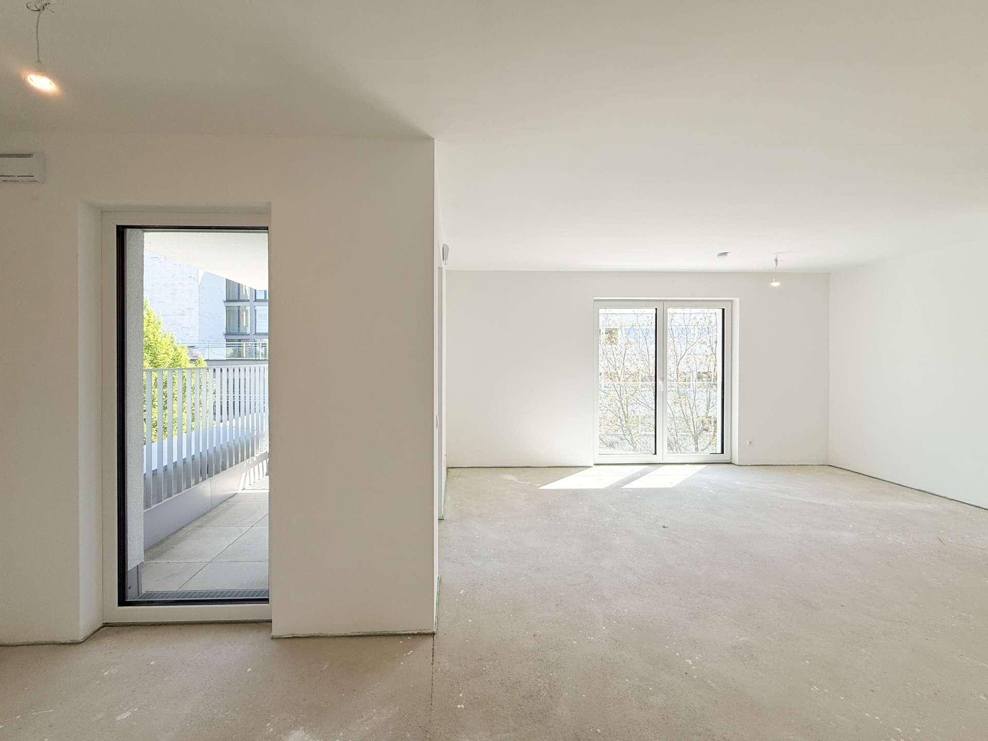 Geräumiger, unmöblierter Raum mit Balkonzugang und viel Tageslicht.
