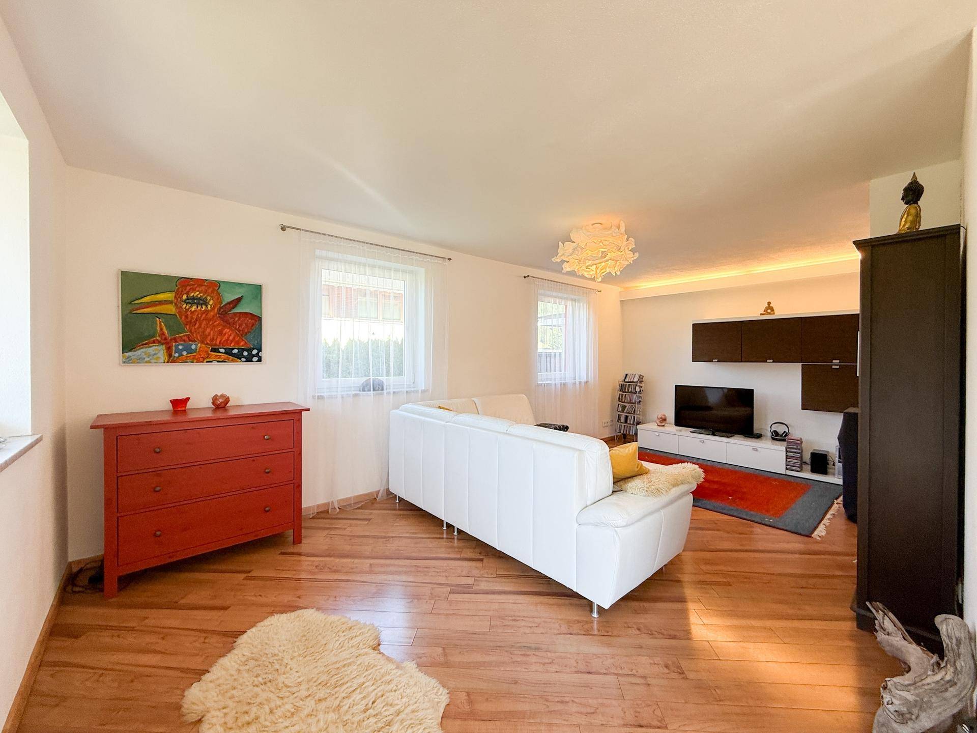 Helles Wohnzimmer mit Holzboden, bequemer Couch und moderner Dekoration.