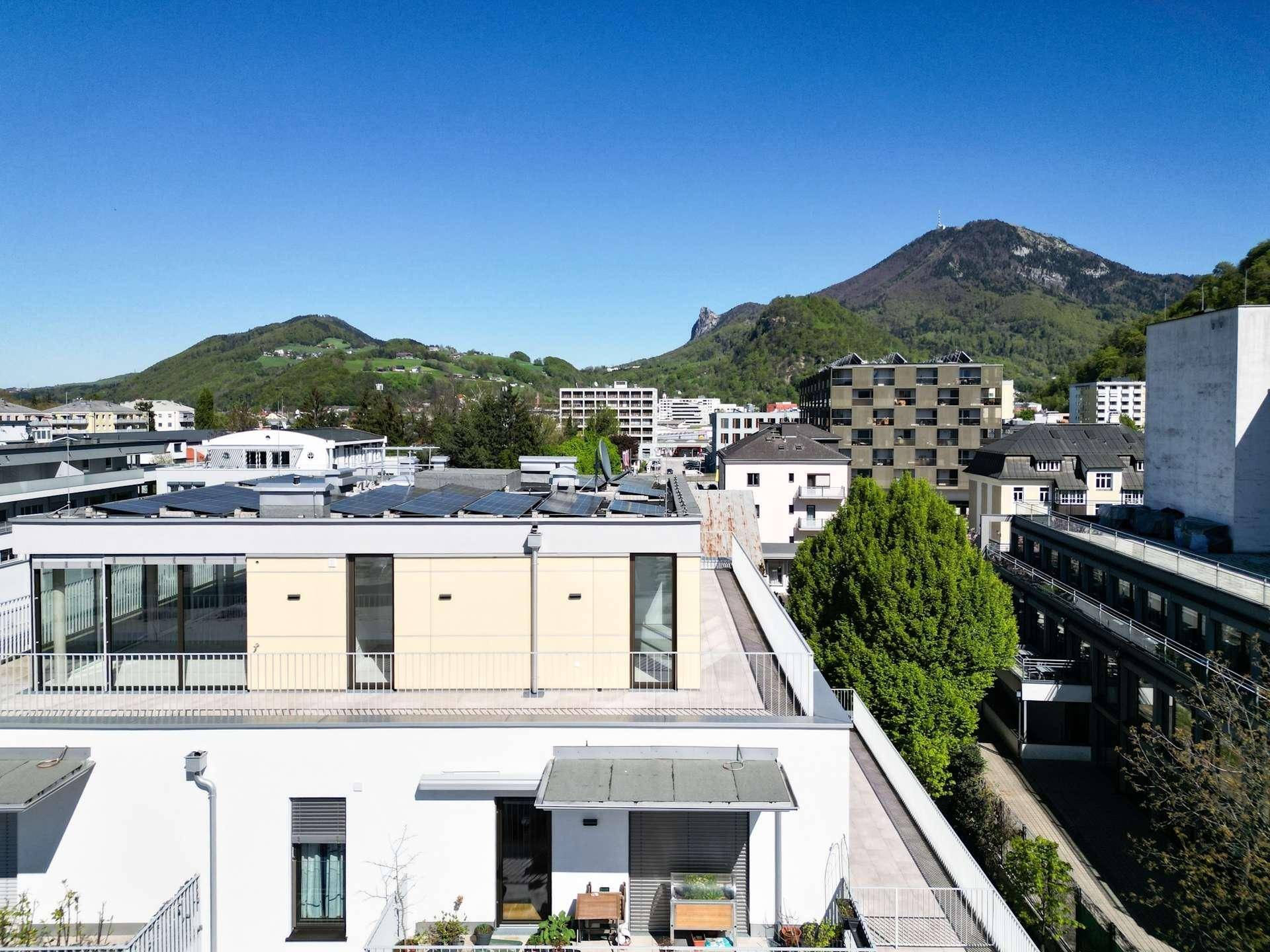 Panoramablick auf eine moderne Wohnanlage mit Bergen im Hintergrund und städtischer Umgebung.