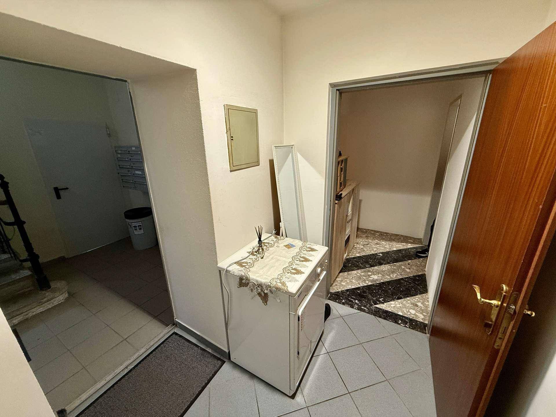 Eingangsbereich mit gefliestem Boden und Zugang zu weiteren Räumen und einer Treppe.