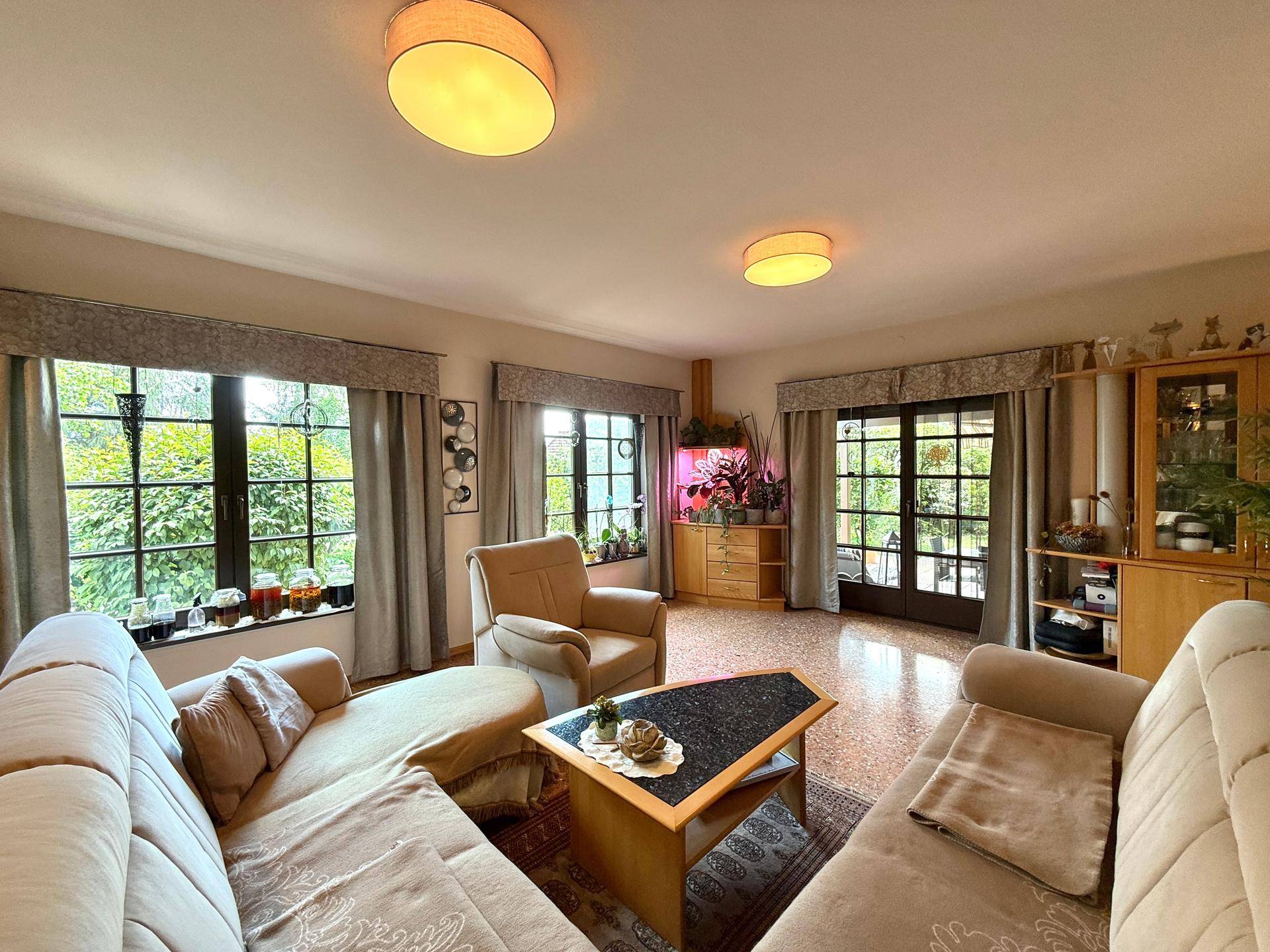 Helles Wohnzimmer mit bequemen Sofas, großen Fenstern und direktem Zugang zur Terrasse.