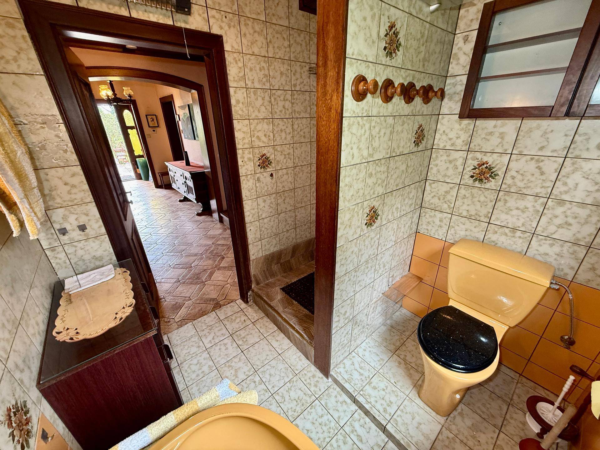 Badezimmer im Stil der 80er Jahre mit gelben Sanitärobjekten und gemusterten Wandfliesen.