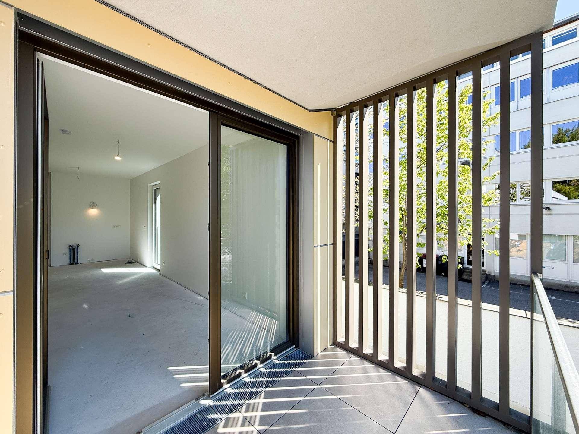 Heller Balkon mit modernen Lamellen und Schiebetür zum Innenraum der Wohnung.