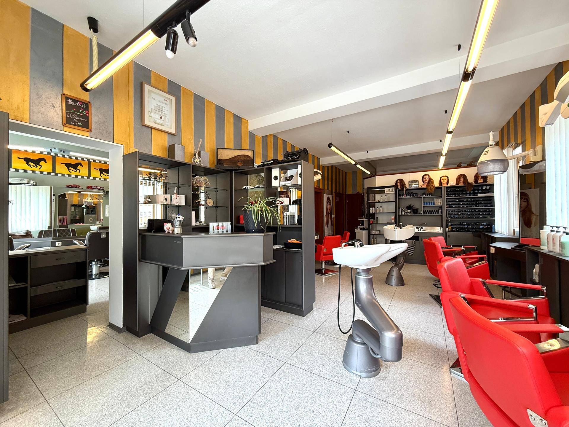 Empfangsbereich eines Friseursalons mit modernen Möbeln und professioneller Einrichtung.