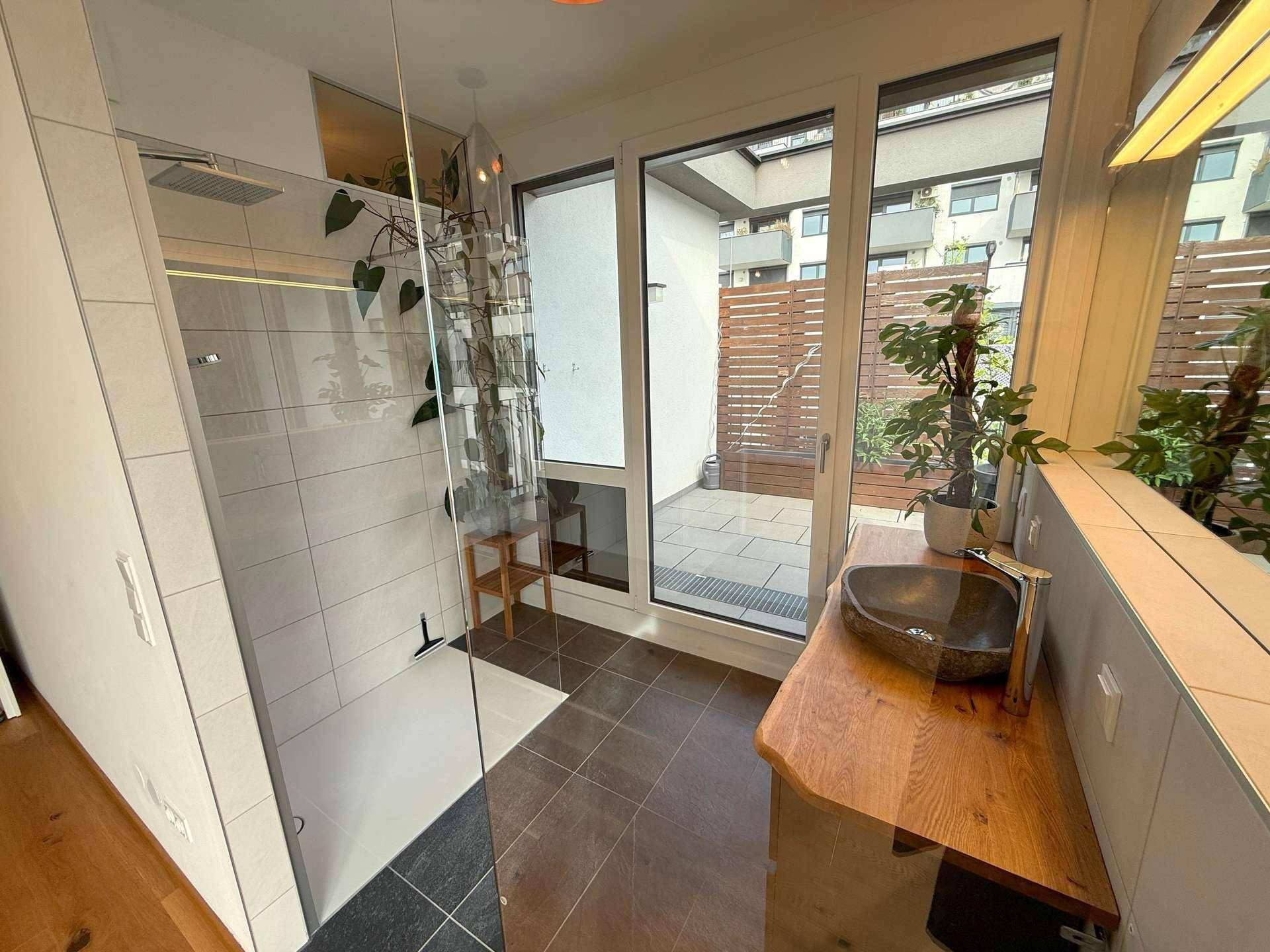 Modernes Badezimmer mit begehbarer Dusche, einzigartigem Waschbecken und Zugang zu einem Außenbereich.
