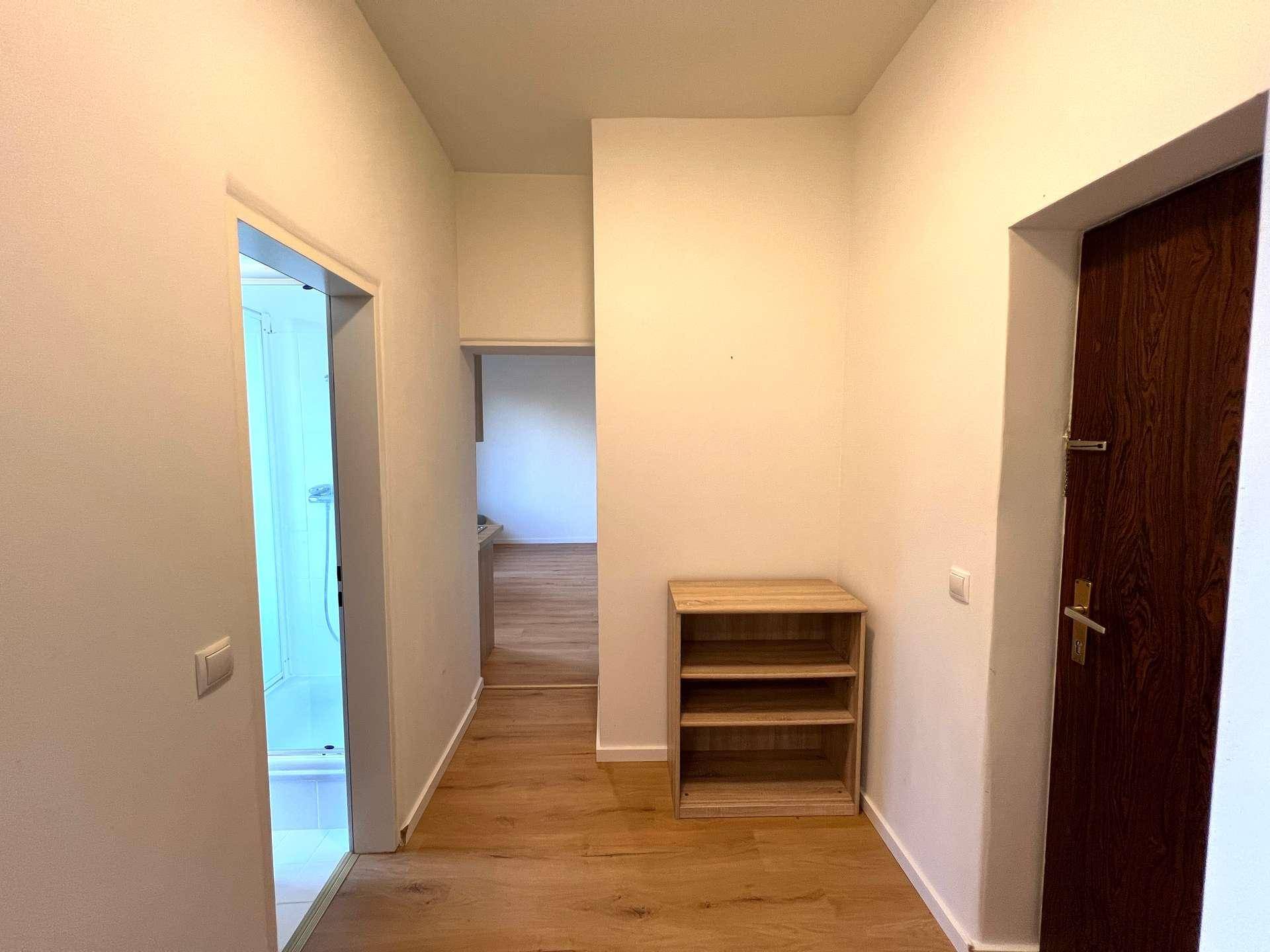 Heller Flur mit Laminatboden und Zugang zu weiteren Zimmern, inklusive einem Badezimmer.