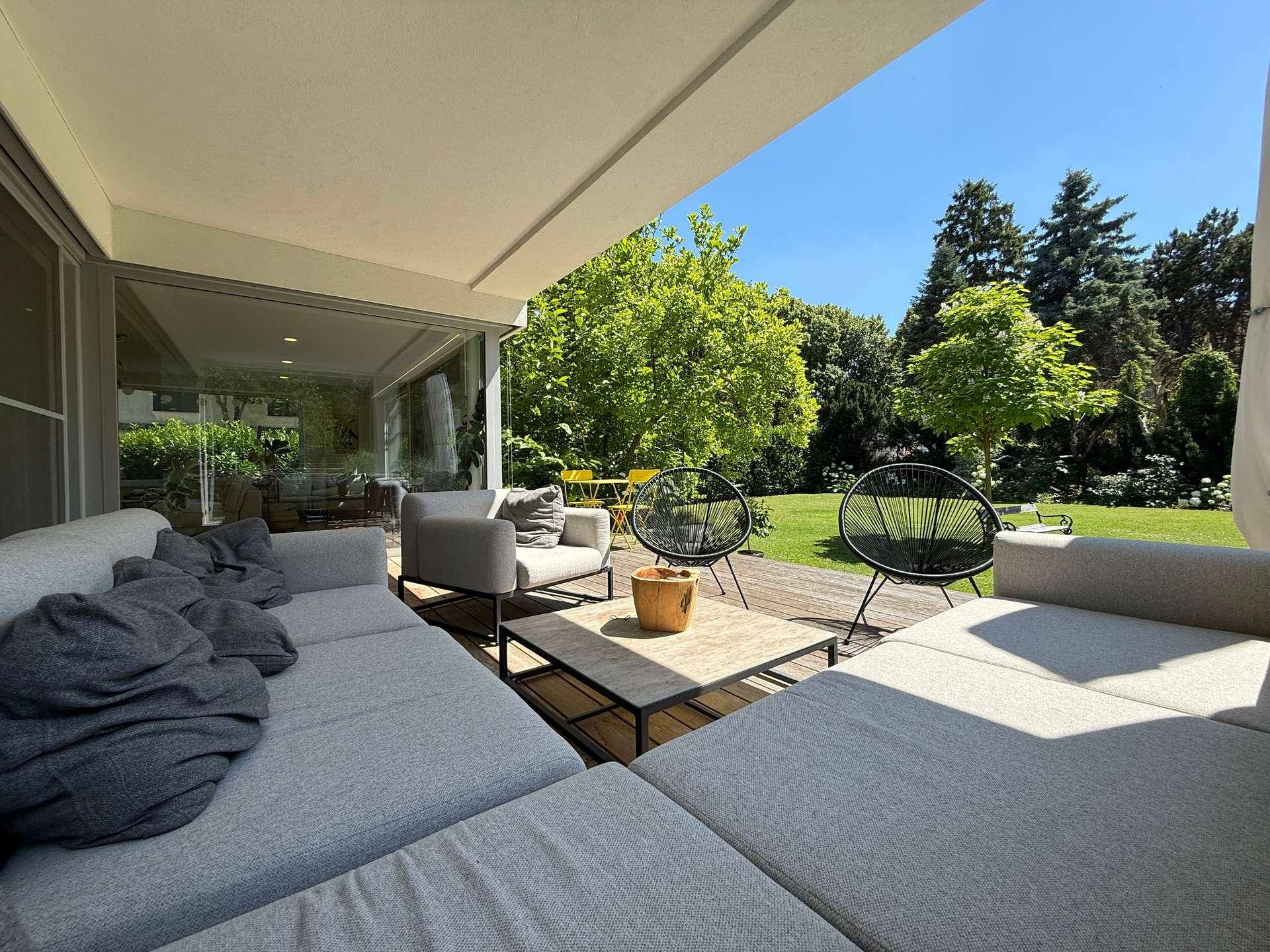 Geräumige Terrasse mit modernen Gartenmöbeln und Blick auf den gepflegten Garten.
