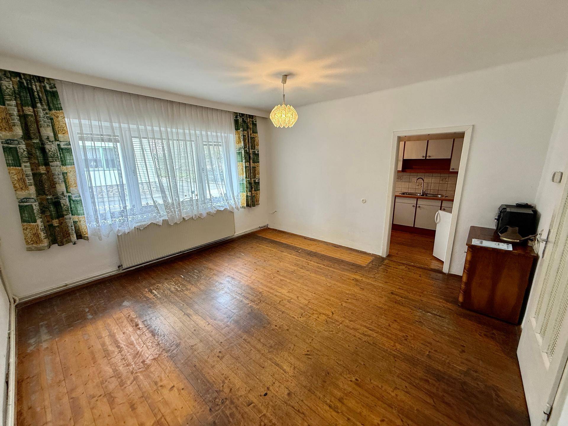 Wohnraum mit Holzdielenboden und Blick in eine angrenzende Küche.
