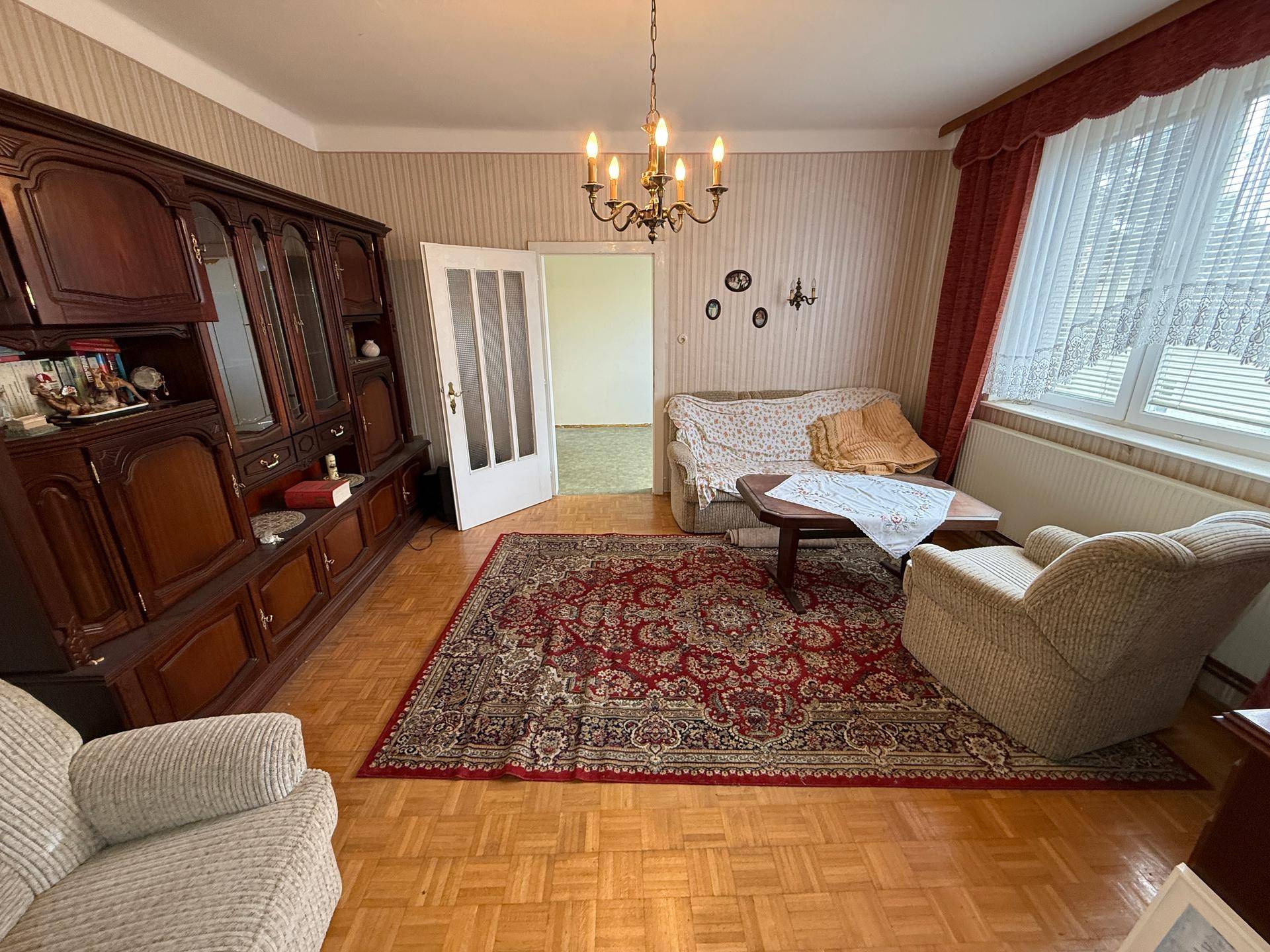 Gemütliches Wohnzimmer mit Parkettboden, traditionellen Möbeln und einem großen Teppich.