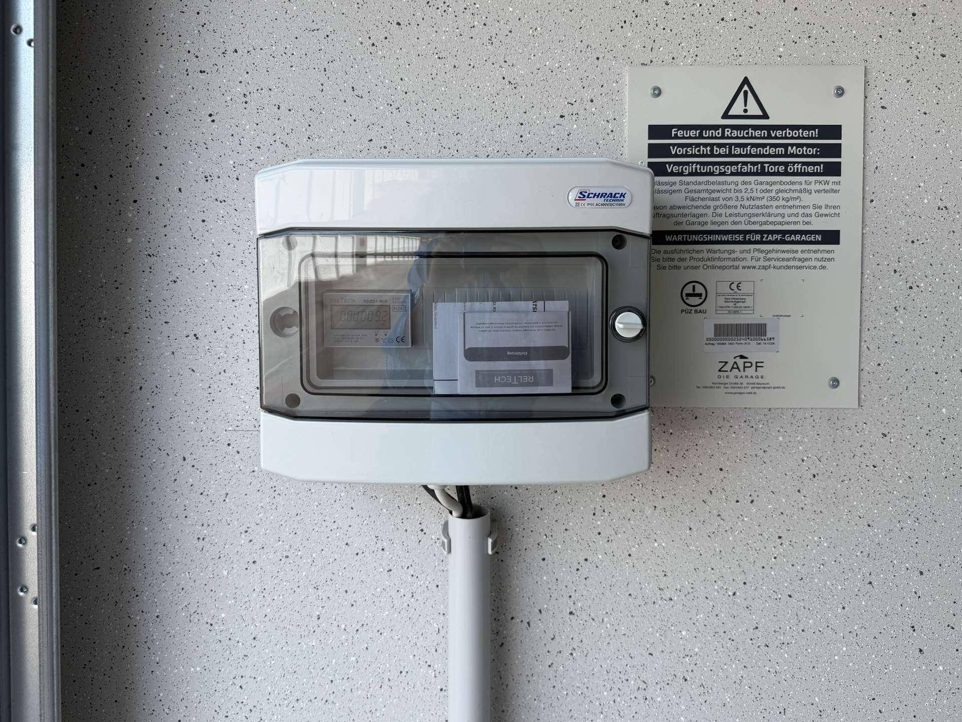 Detailansicht eines Stromzählers und Warnhinweisen in der Garagenbox.