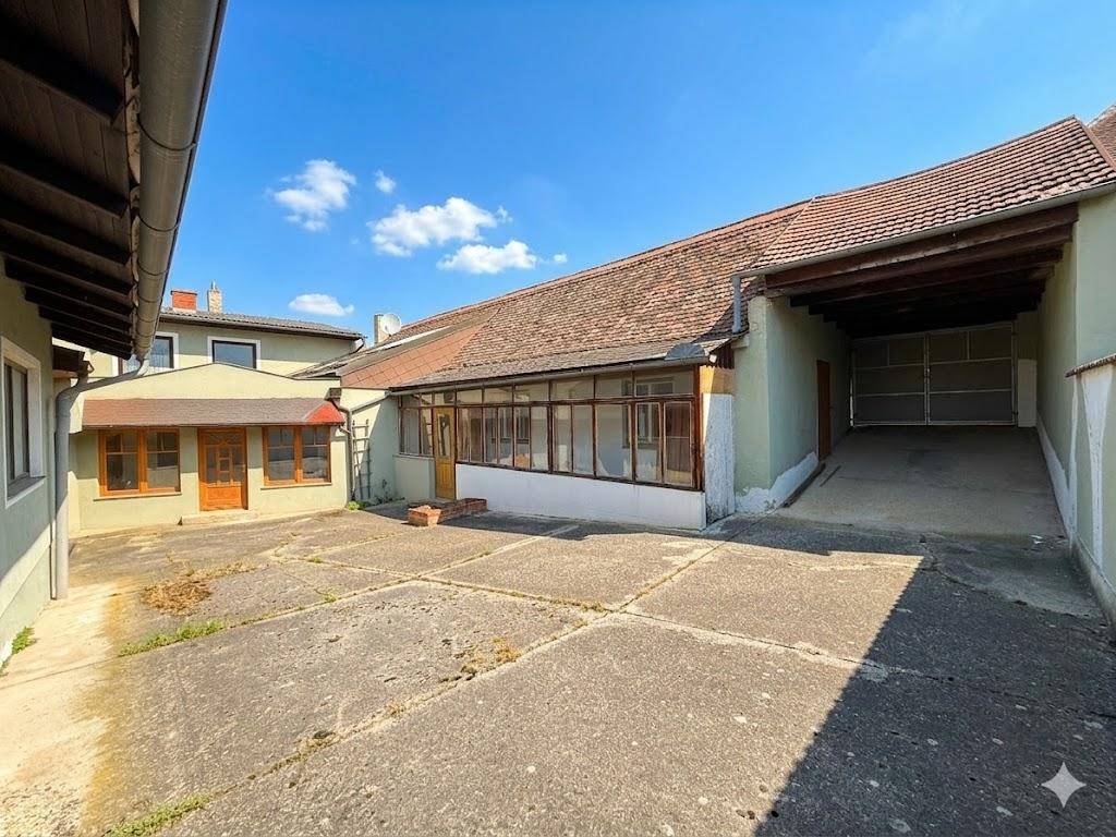 Gepflasterter Innenhof zwischen den Gebäudeteilen mit Zugang zu einem überdachten Bereich.