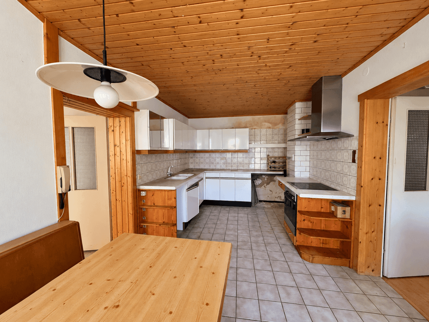 Rustikale Küche mit Holzdecke, Fliesenboden und Essbereich.