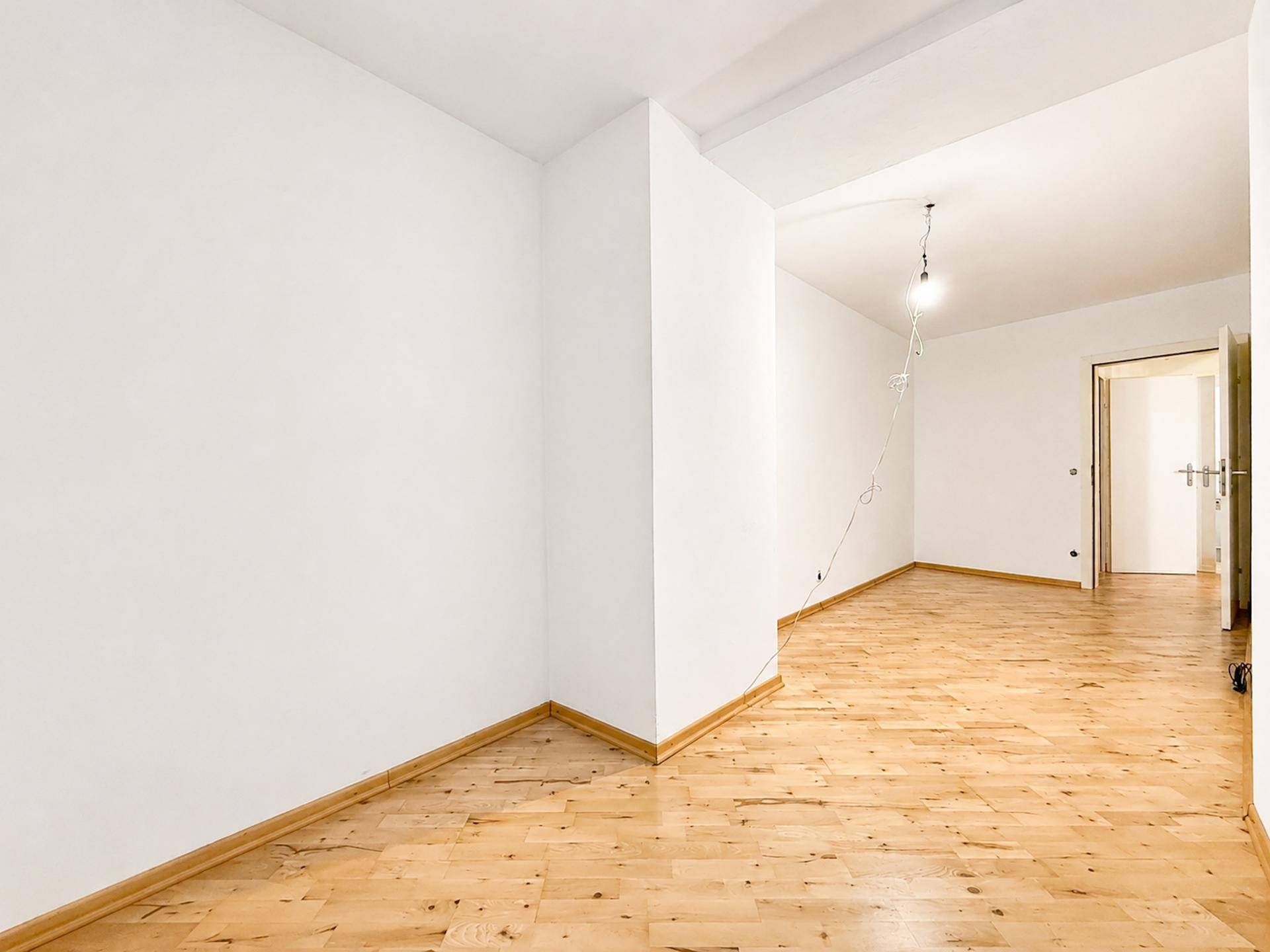 Leerer Raum mit Holzboden und weiß gestrichenen Wänden, bereit zur Einrichtung.