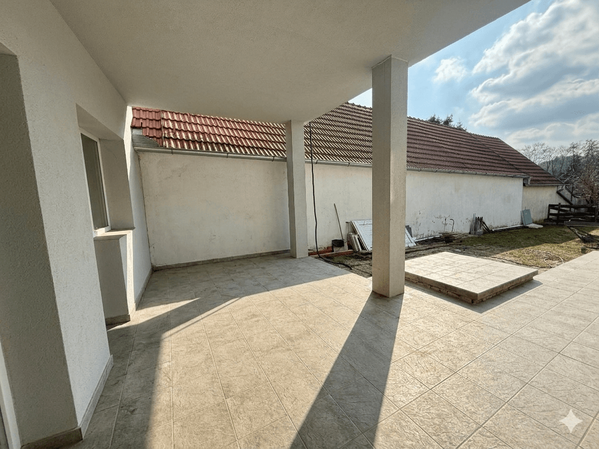 Überdachte Terrasse mit Fliesenboden und Blick auf den Hinterhof.