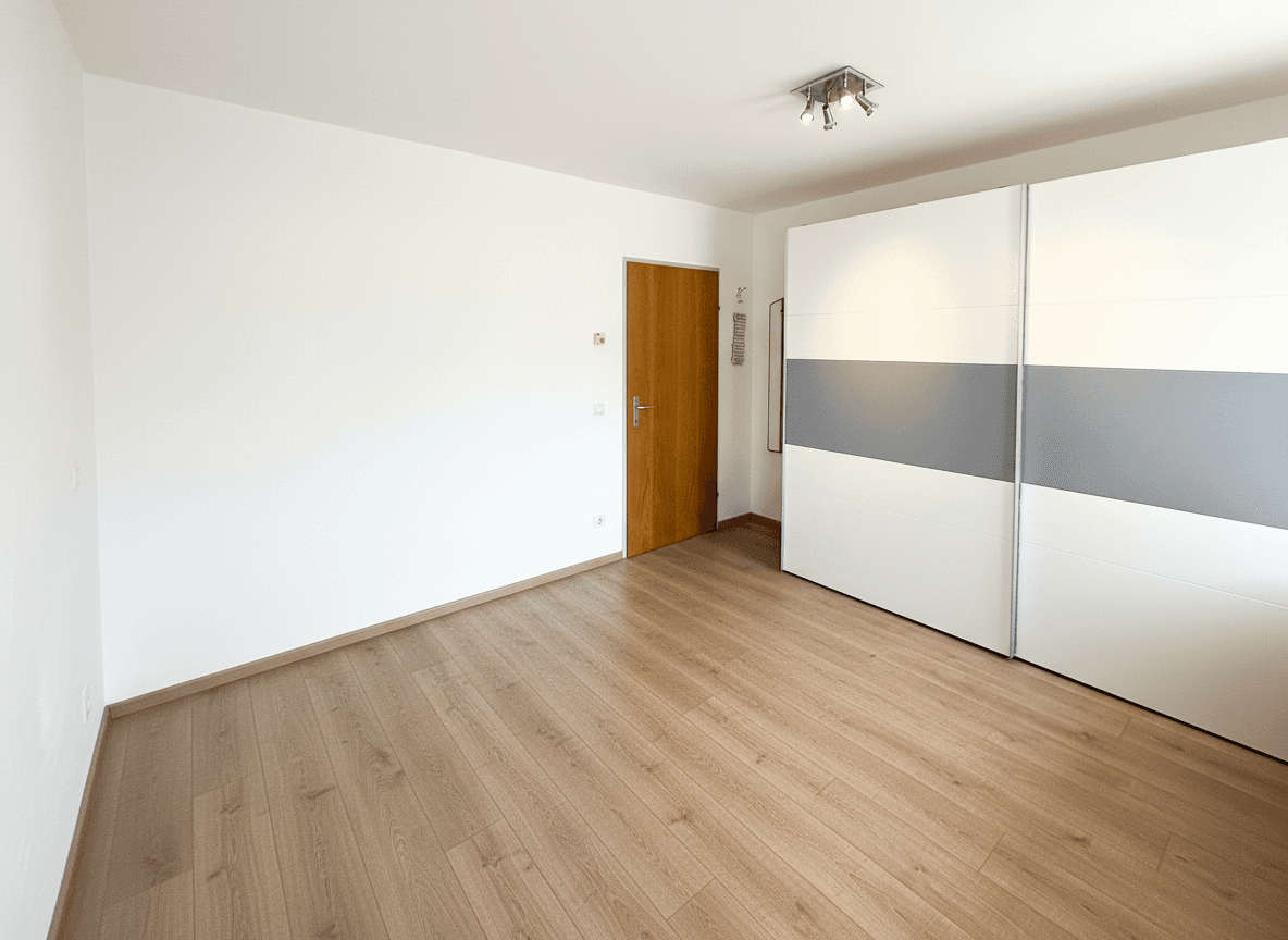 Geräumiges Schlafzimmer mit hellem Holzboden und großem, praktischem Schiebetürenschrank.