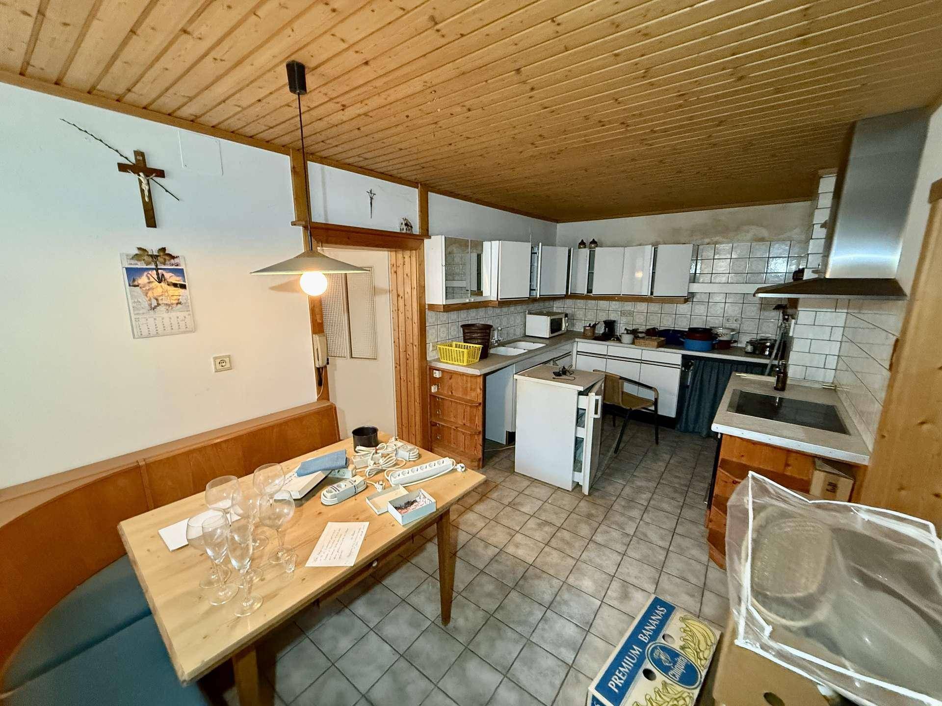Gemütliche Küche mit Essbereich, Holzdecke und Fliesenboden, ideal für Familienmahlzeiten.