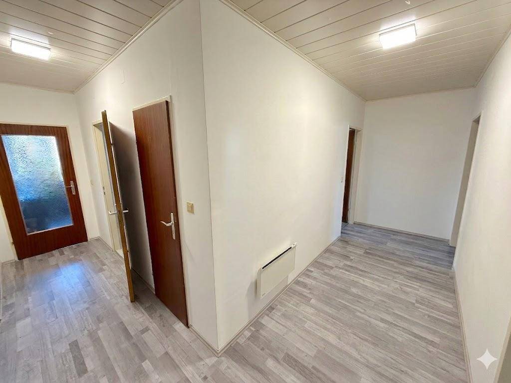 Heller Flur mit Laminatboden und mehreren Türen, der verschiedene Räume verbindet.