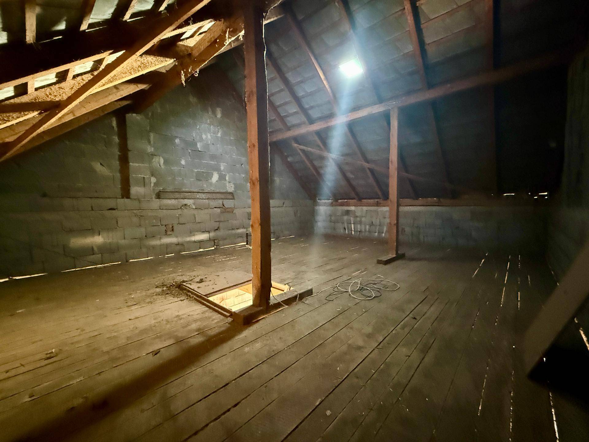 Unausgebauter Dachboden mit Holzboden und sichtbaren Dachbalken, bietet Ausbaupotenzial.