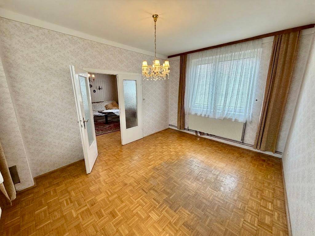 Geräumiges Wohnzimmer mit Parkettboden, Tapeten und einem Kronleuchter.