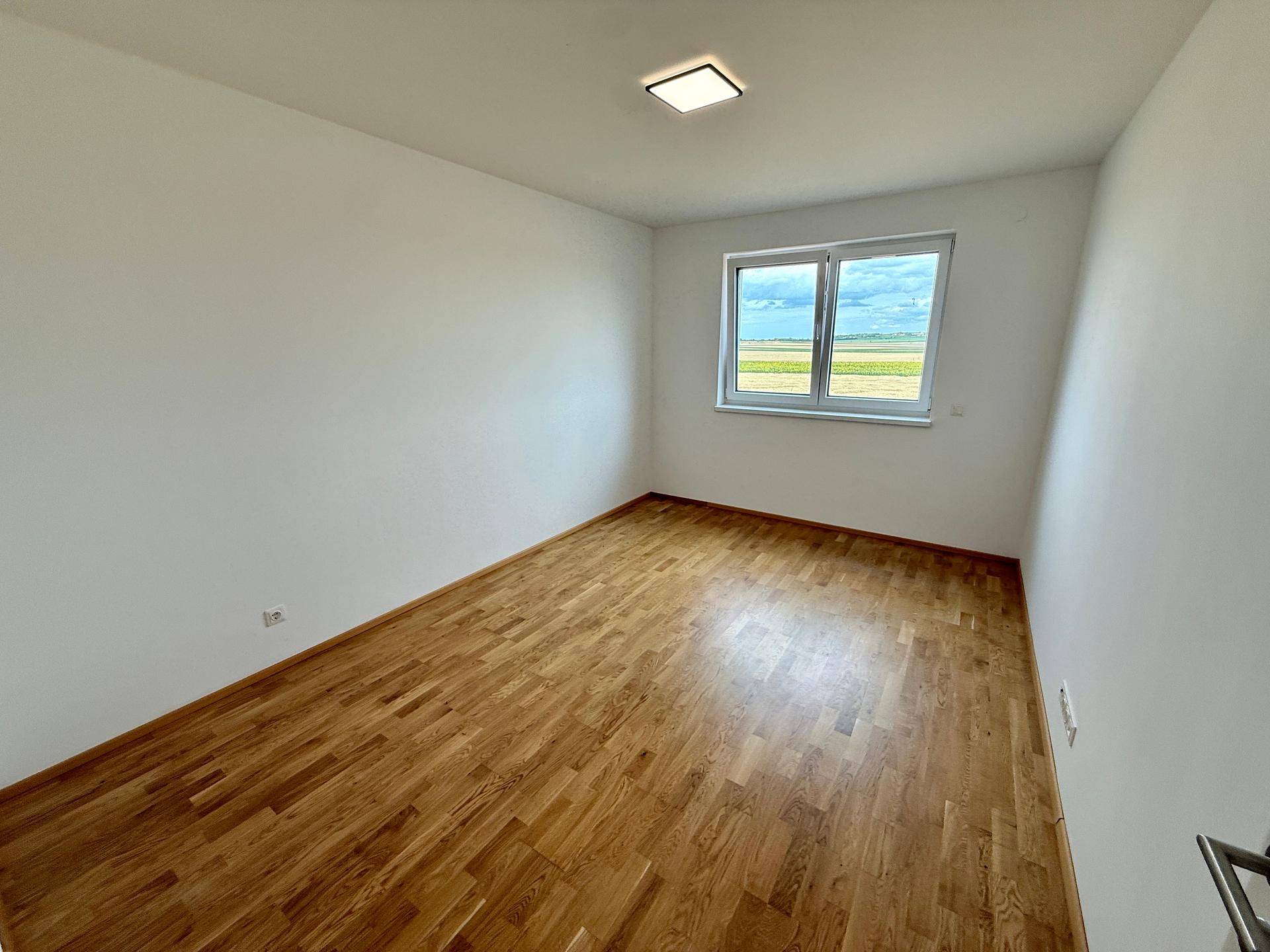 Geräumiges Schlafzimmer mit Holzboden und weitem Blick über die Landschaft.