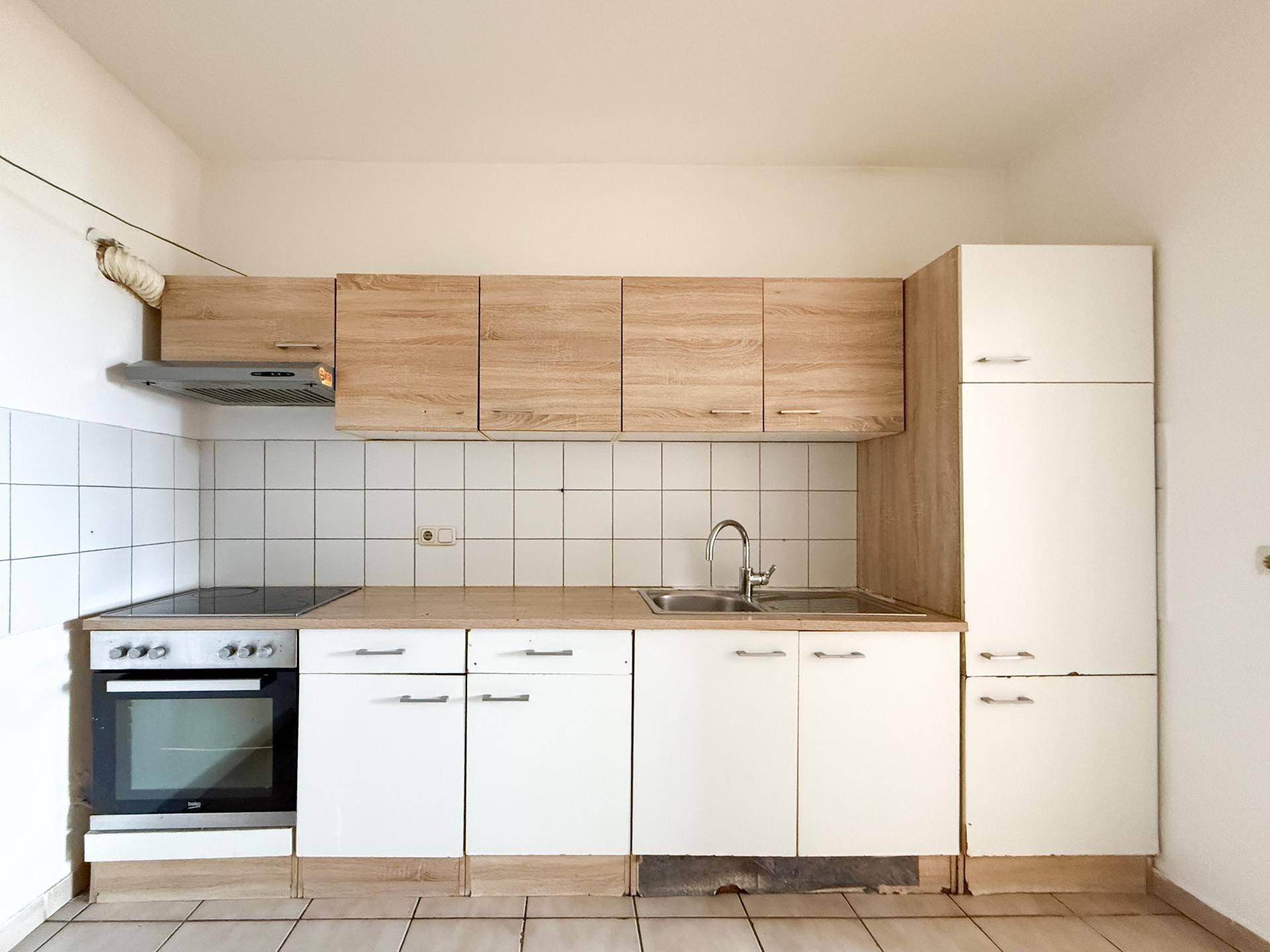 Funktionale Küche mit hellen Holz- und weißen Fronten, ausgestattet mit Herd und Spüle.