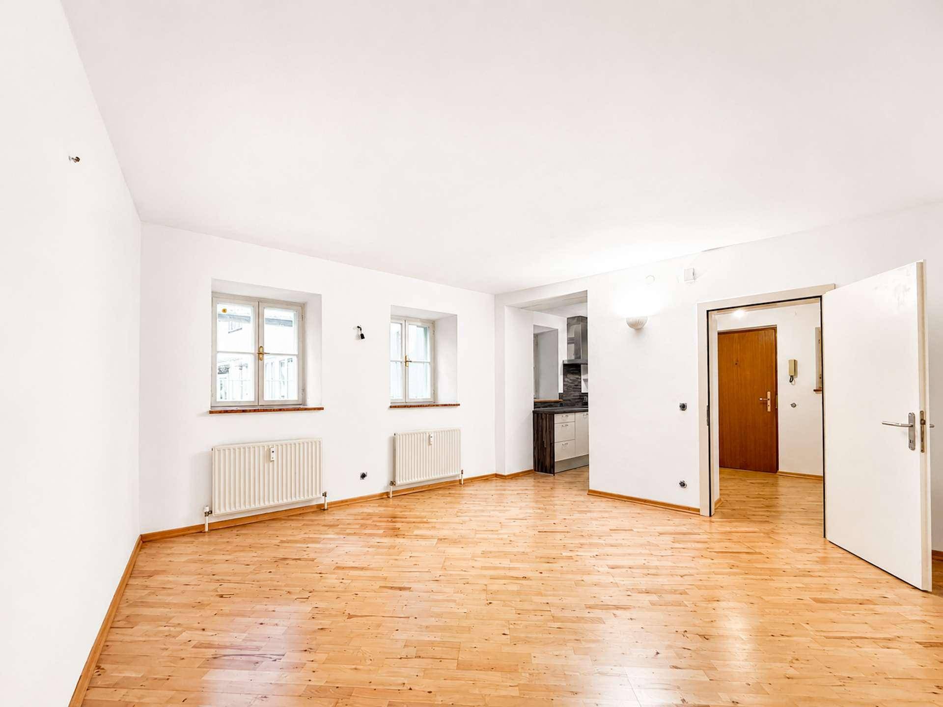 Heller Wohnraum mit Holzboden und zwei Fenstern, bietet vielseitige Gestaltungsmöglichkeiten.
