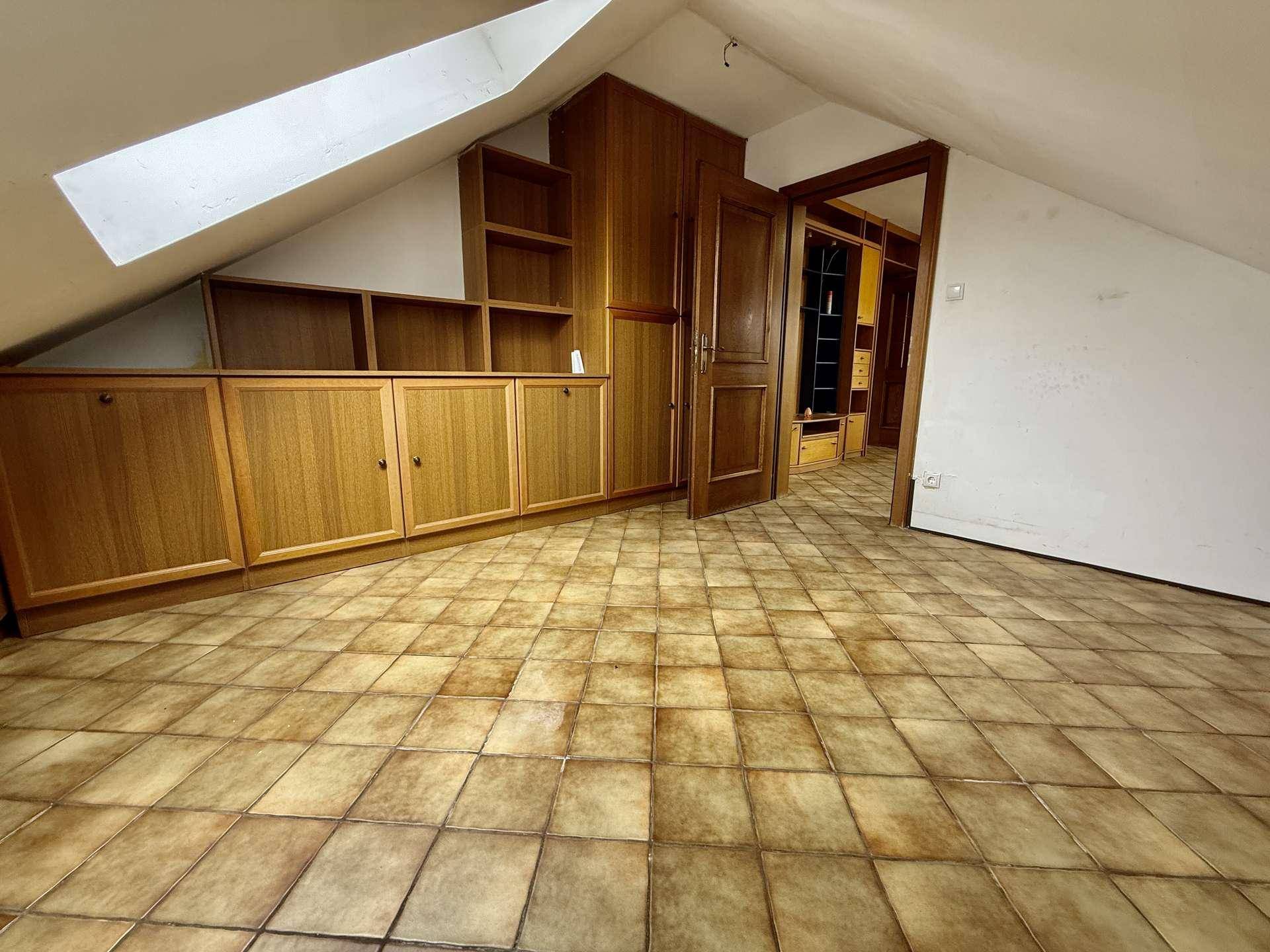Dachzimmer mit schrägen Wänden, Einbauschränken und Fliesenboden.