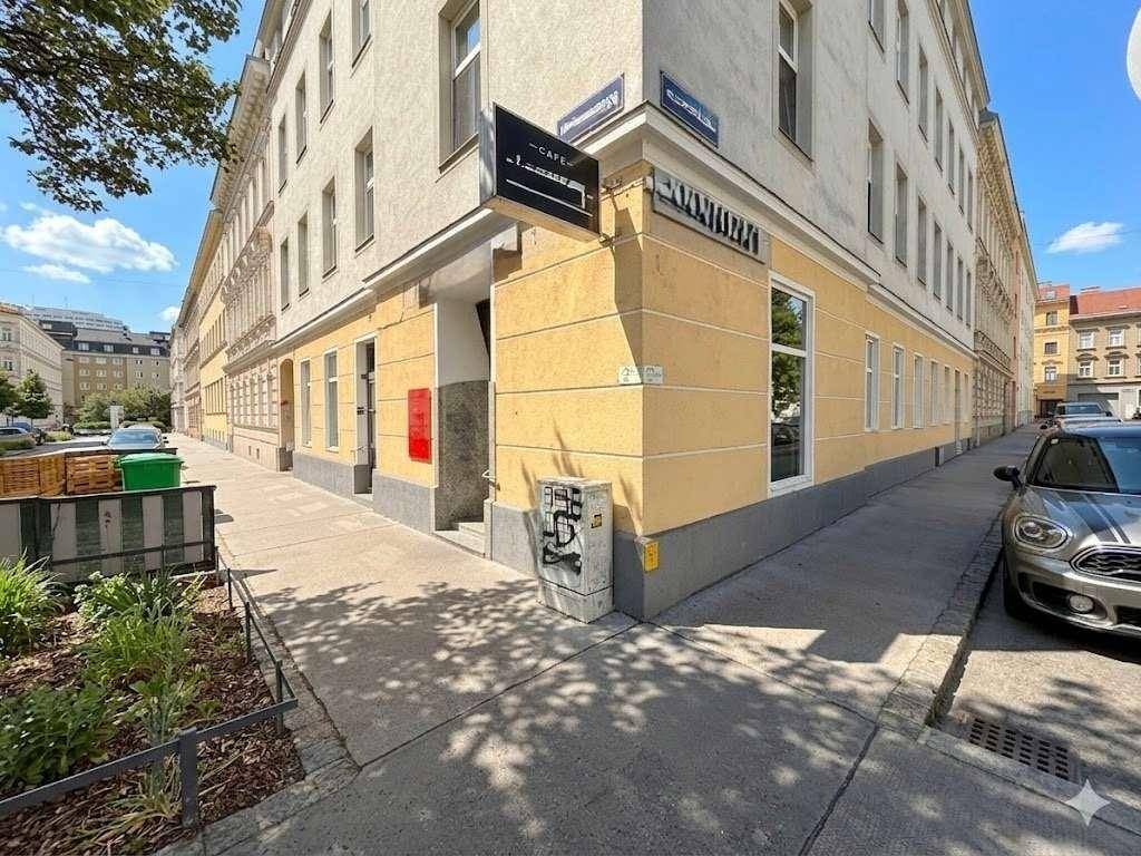 Außenansicht eines Eckgebäudes mit Gewerbefläche im Erdgeschoss und umliegender Stadtlandschaft.