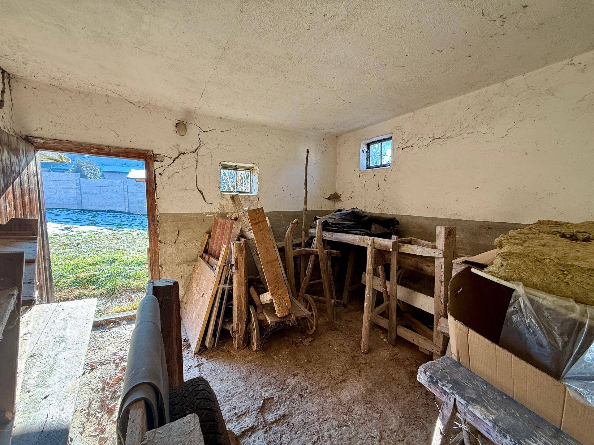 Einfacher Lagerraum mit rauen Wänden und kleinem Fenster, bietet viel Stauraum.