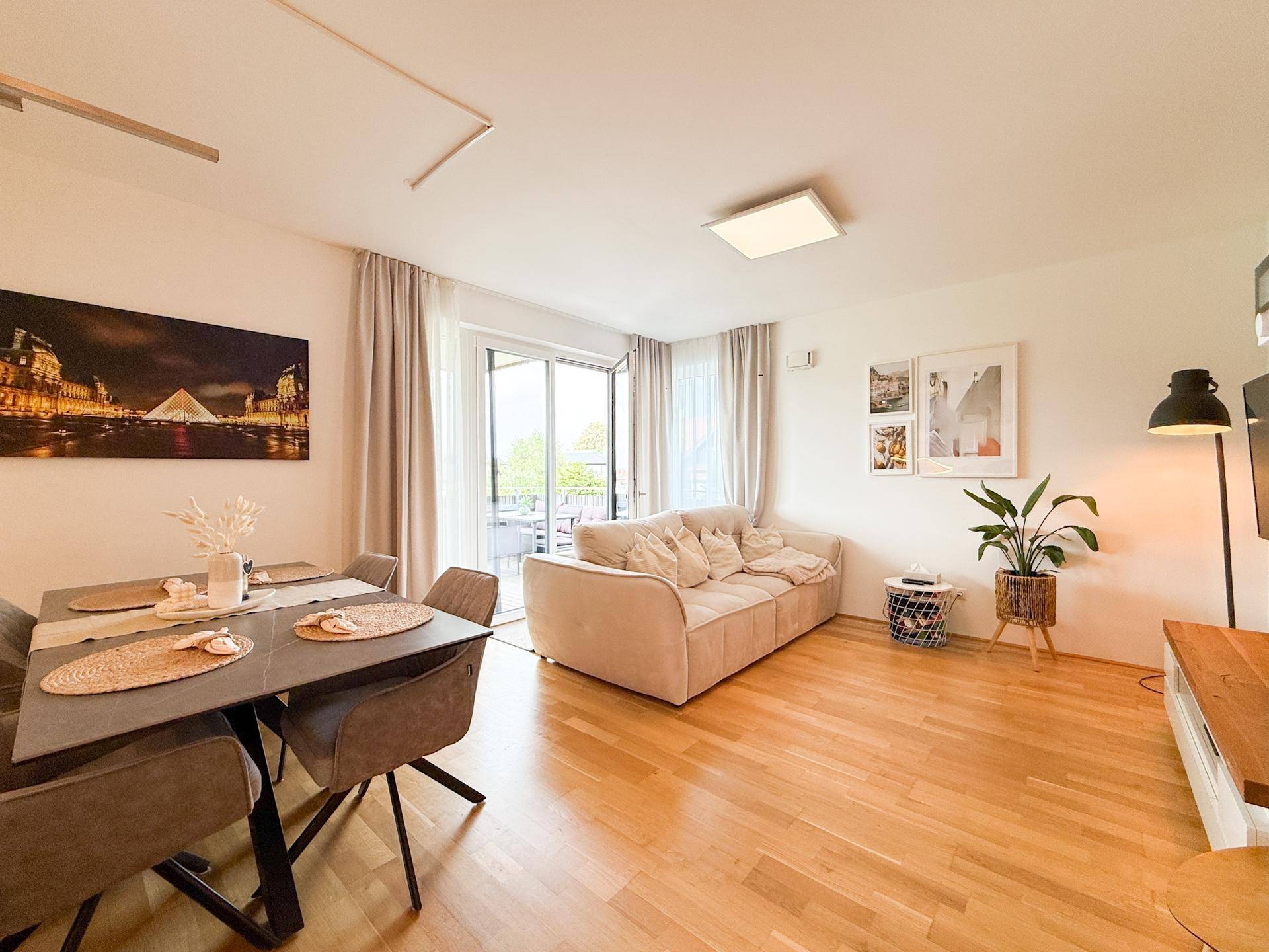 Gemütlicher Wohnbereich mit Sofa, Esstisch und Zugang zum sonnigen Balkon.