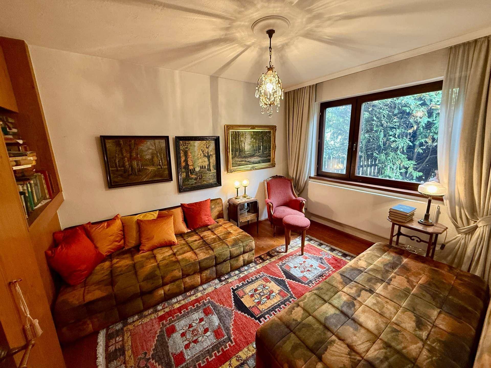 Farbenfrohes Schlafzimmer mit zwei Betten, Teppichen und Blick ins Grüne.