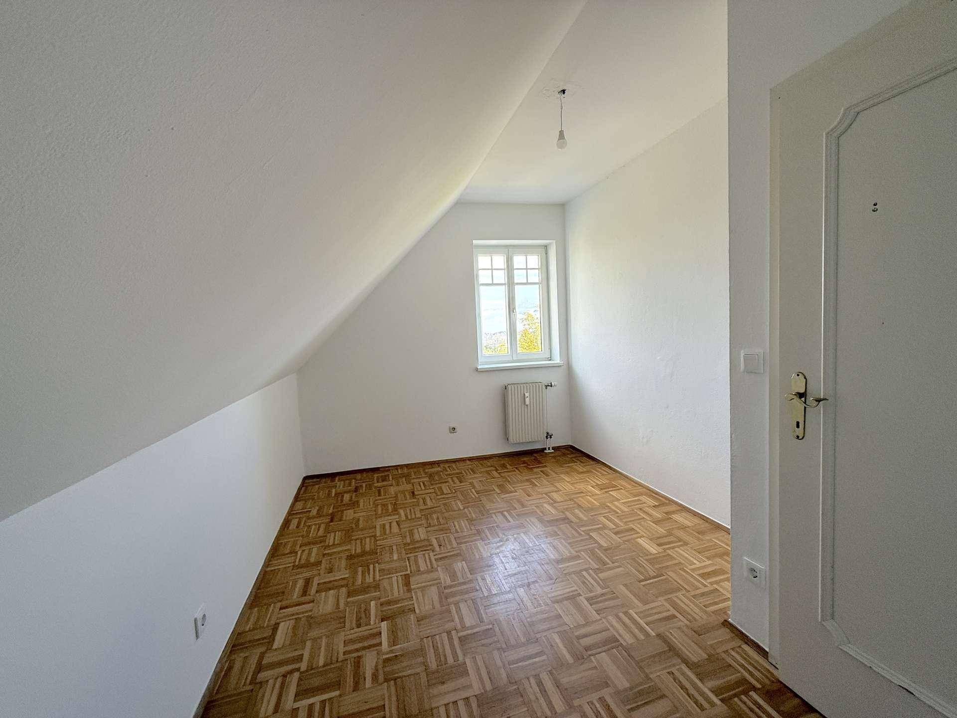 Unmöbliertes Schlafzimmer mit Parkettboden und Dachschräge, ideal für individuelle Gestaltung.