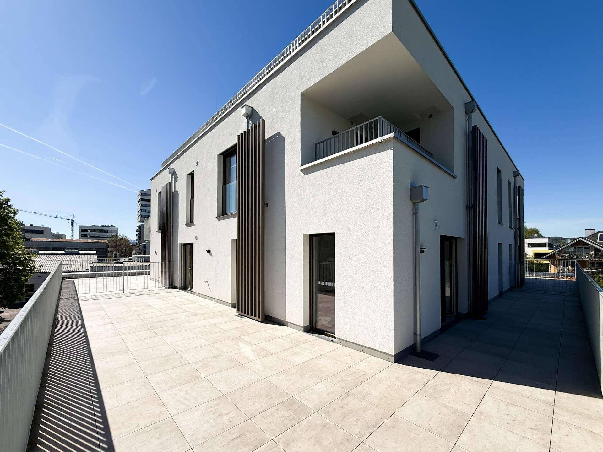 Moderne Architektur des Neubaus mit mehreren Terrassen und Balkonen unter blauem Himmel.